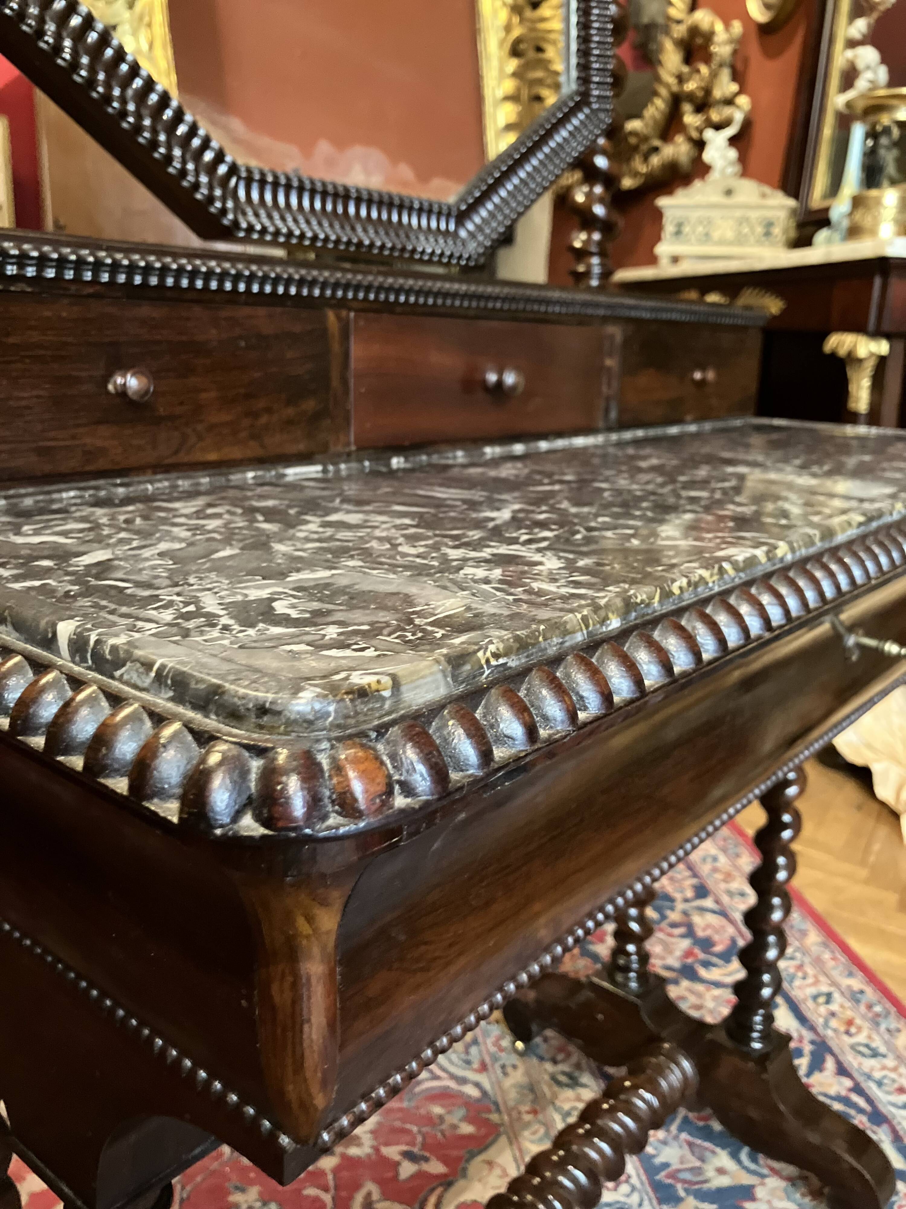 Antique English mahogany dressing table with carved details, black marble, and mirror.