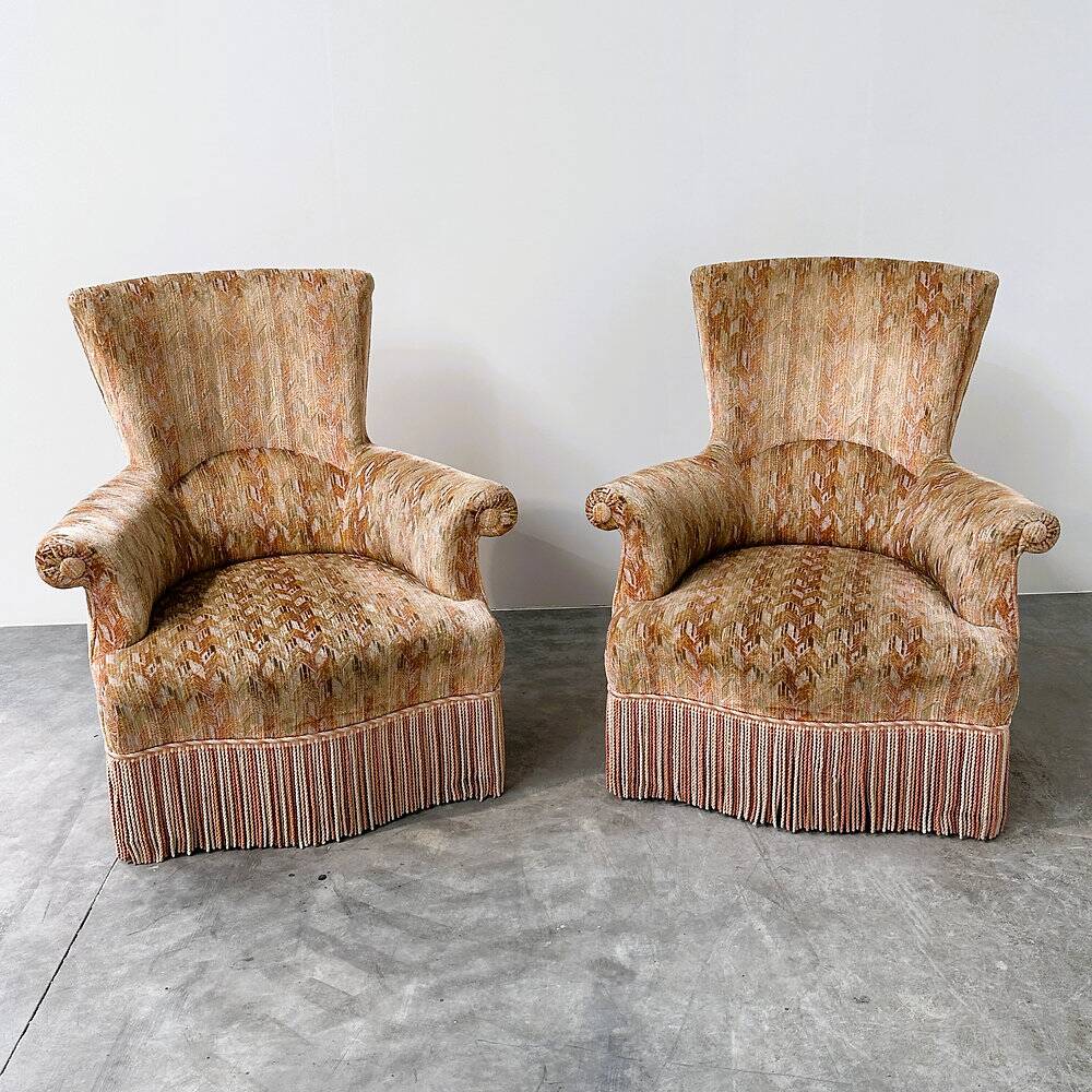 Pair of sculptural Hollywood Regency lounge chairs with original fringed upholstery