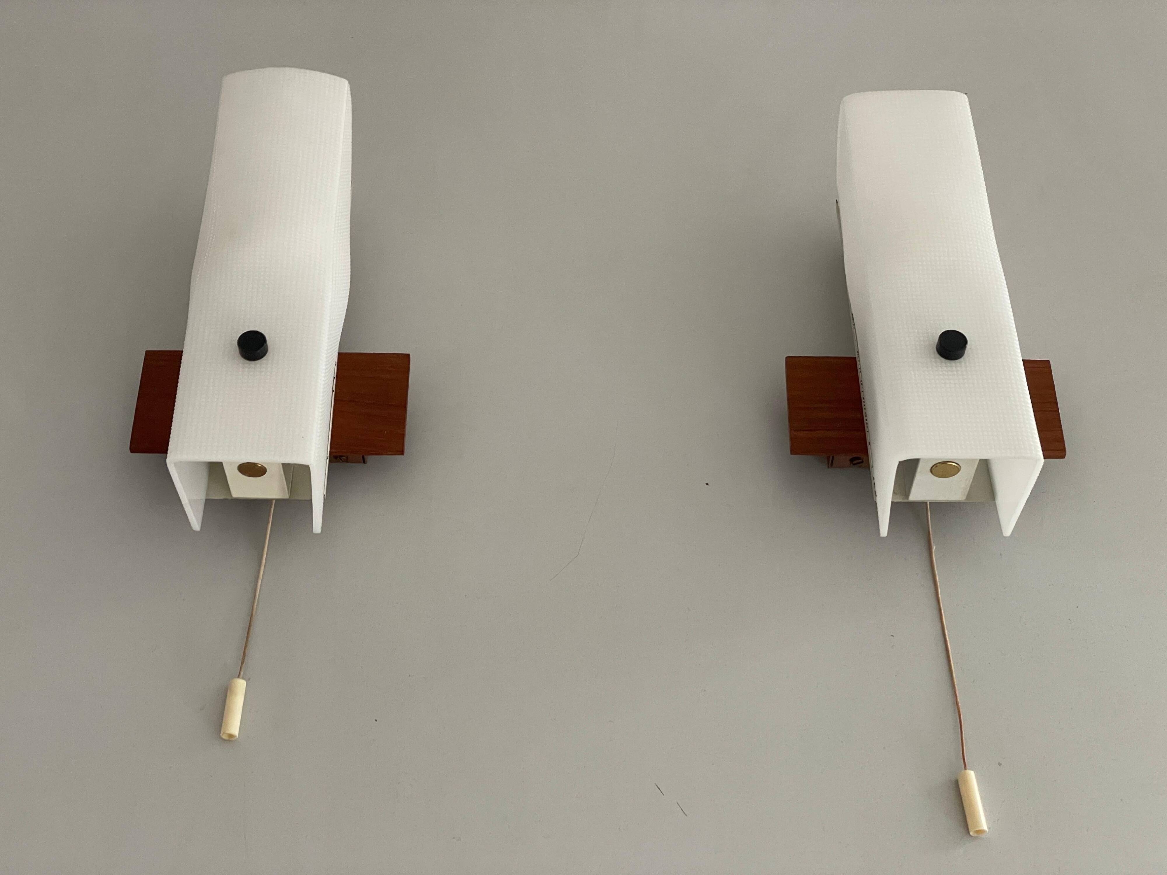 Mid-century wall lights in white plexiglass with a wooden base, 1960s, Germany.