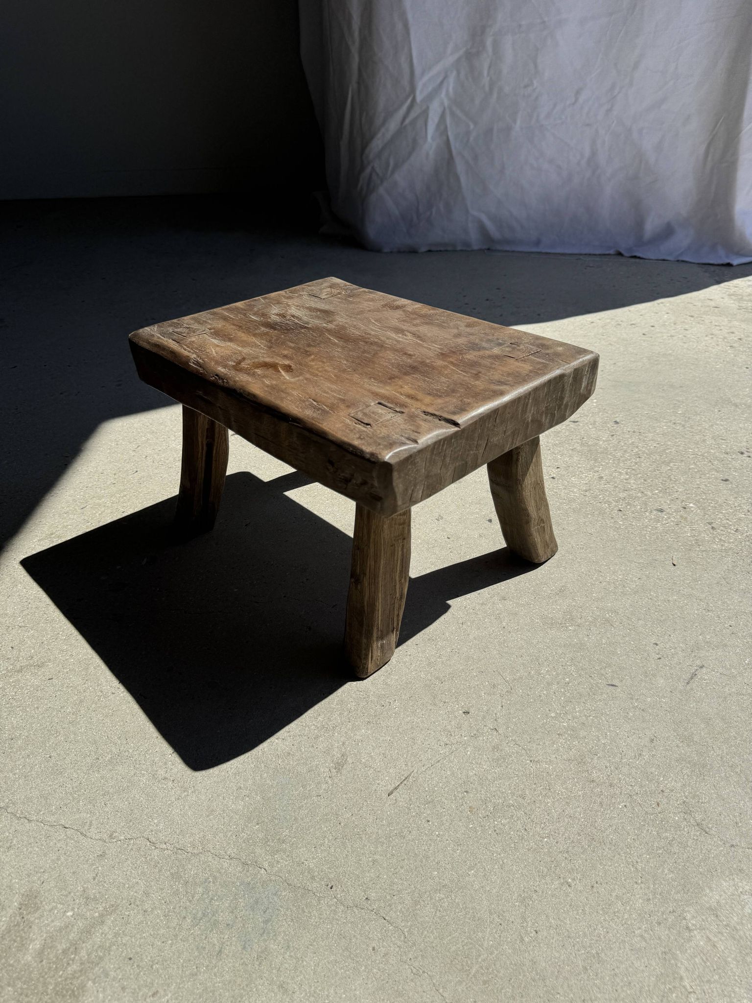 Small stool, rectangular solid teak side table with curved legs.
