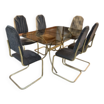 7-piece dining set in gold-plated brass, with a smoked glass top and grey fabric.