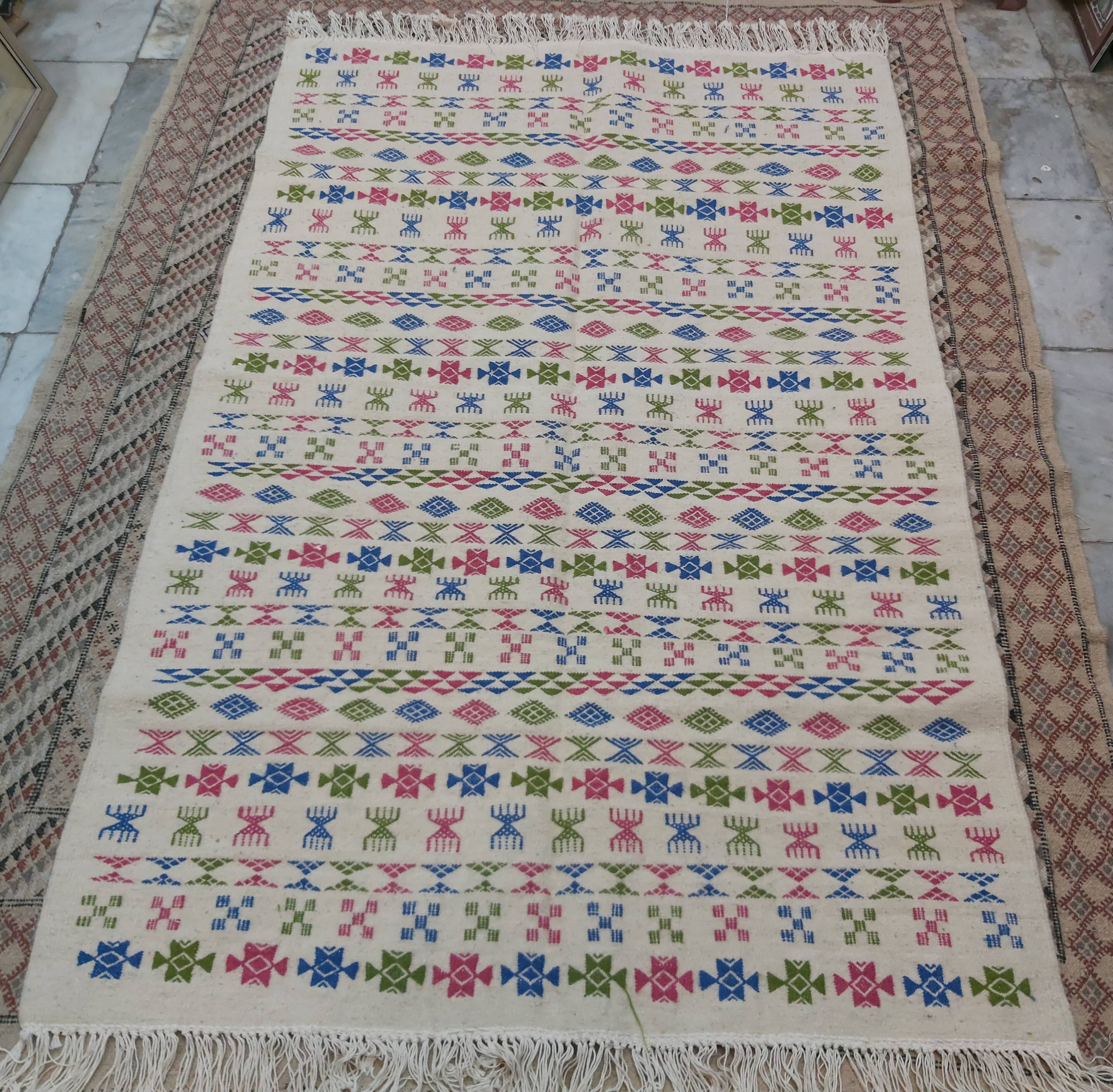 White carpet with Berber motifs pink green and blue