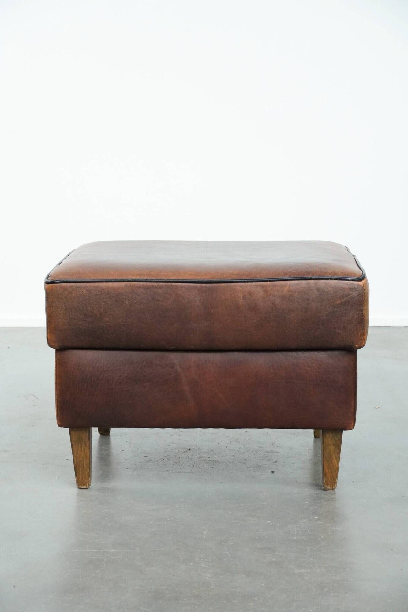Sturdy vintage sheepskin ottoman in a beautiful large size with black piping