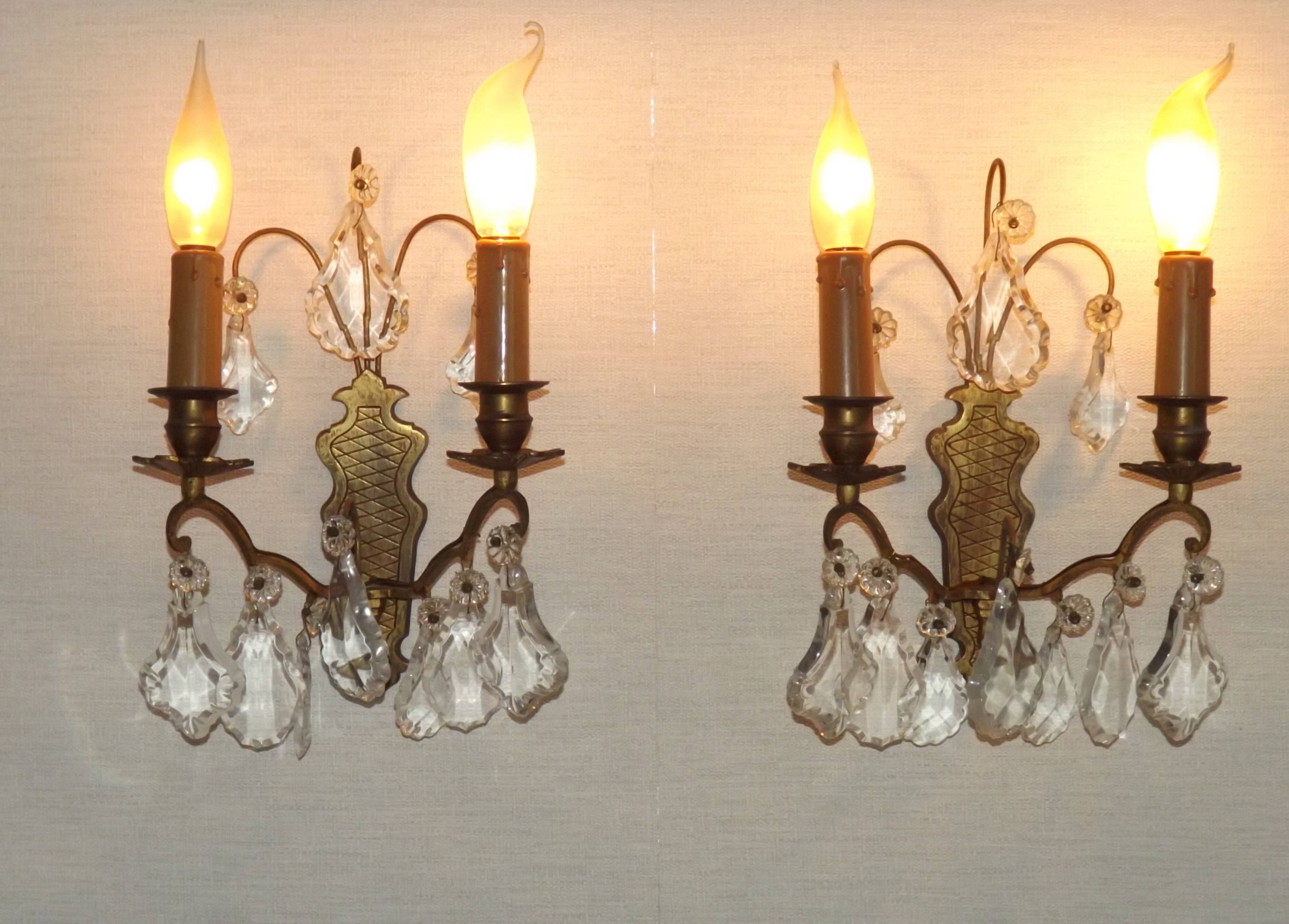 Pair of French antique brass double wall lights with assorted crystals.