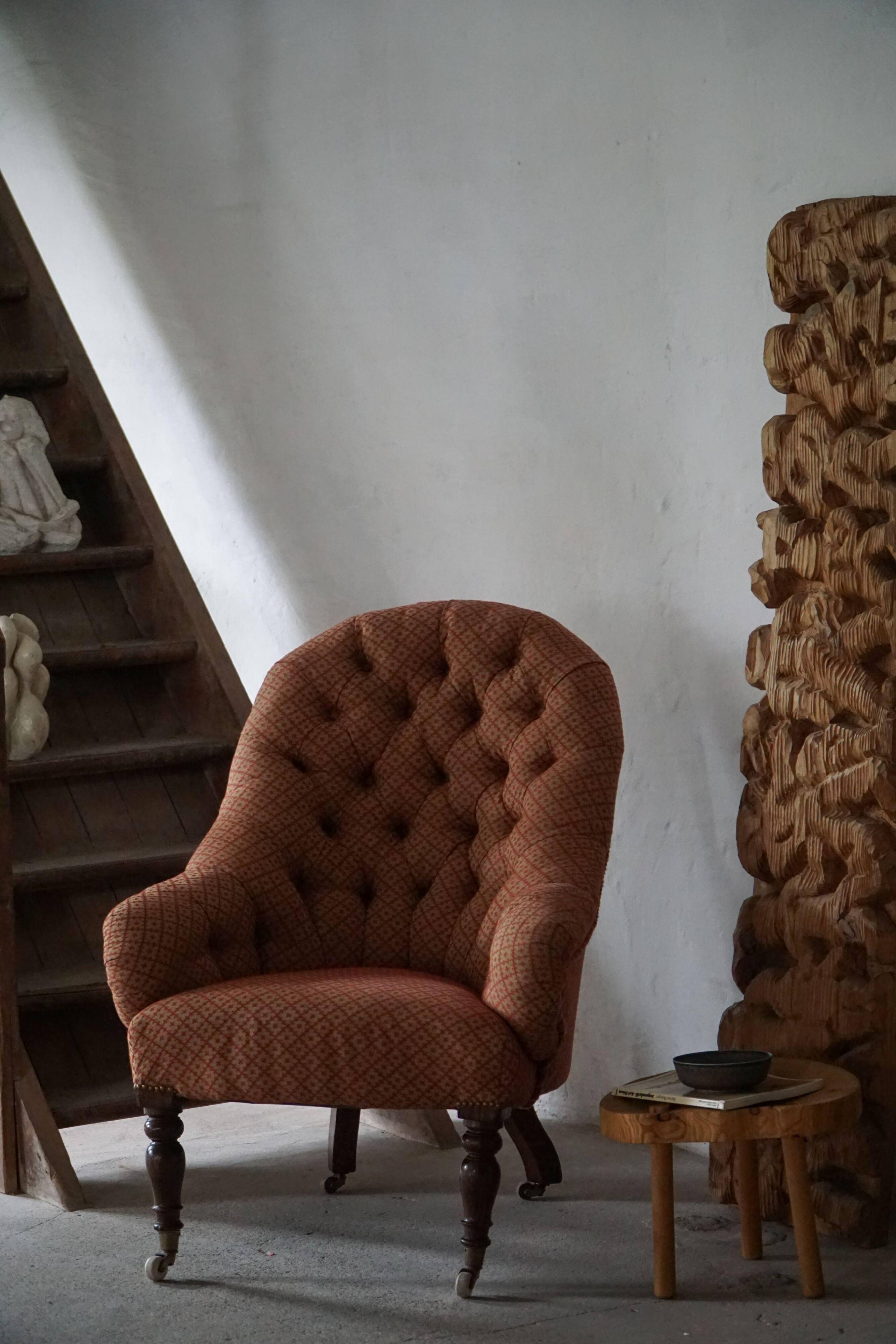 Victorian mahogany armchair, with wheels and coloured fabric, England, early 1900s.