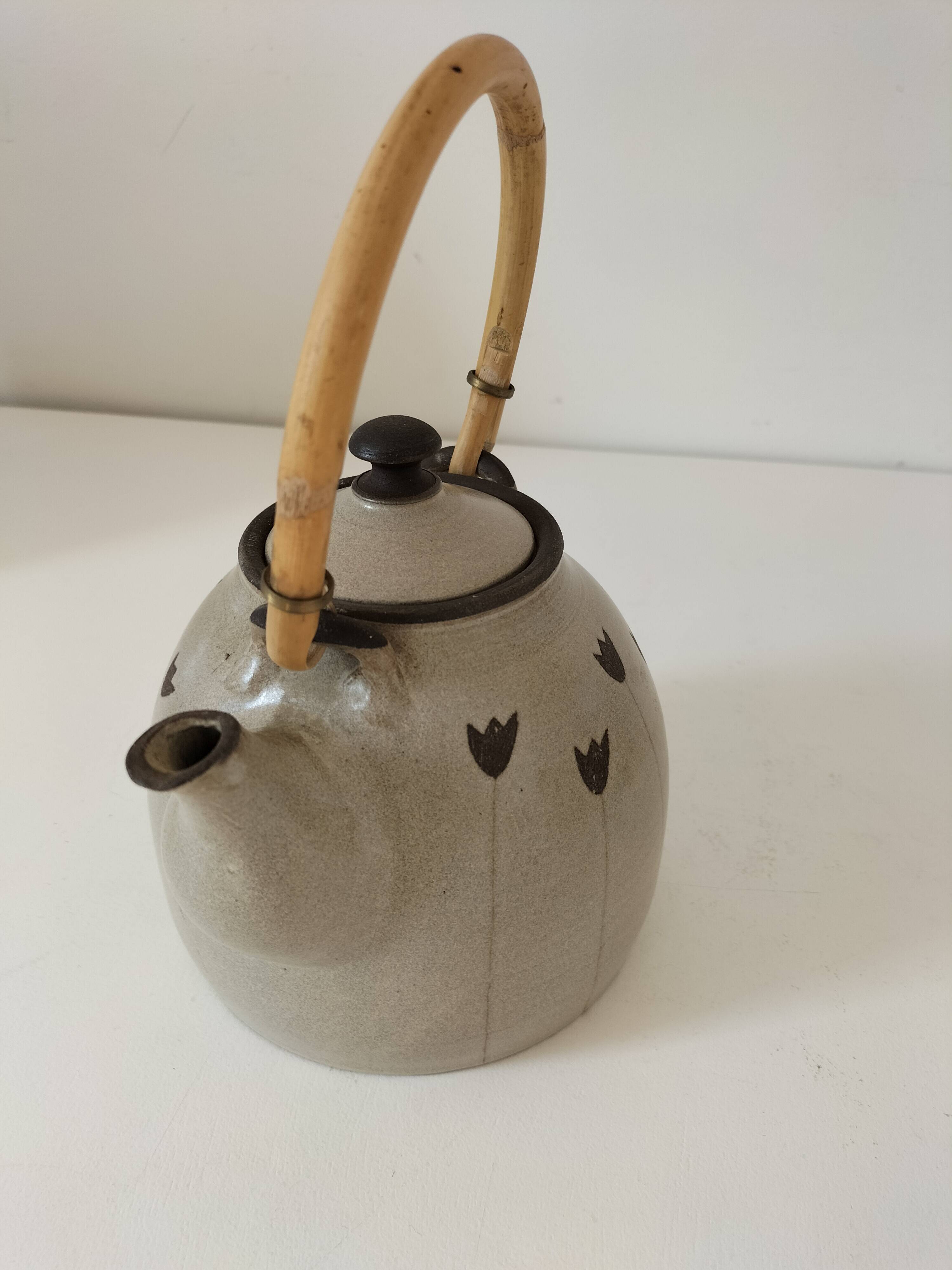 Beige stoneware teapot with stylized flowers and rattan handle