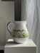 Large white terracotta carafe with a stylized green and yellow frieze pattern