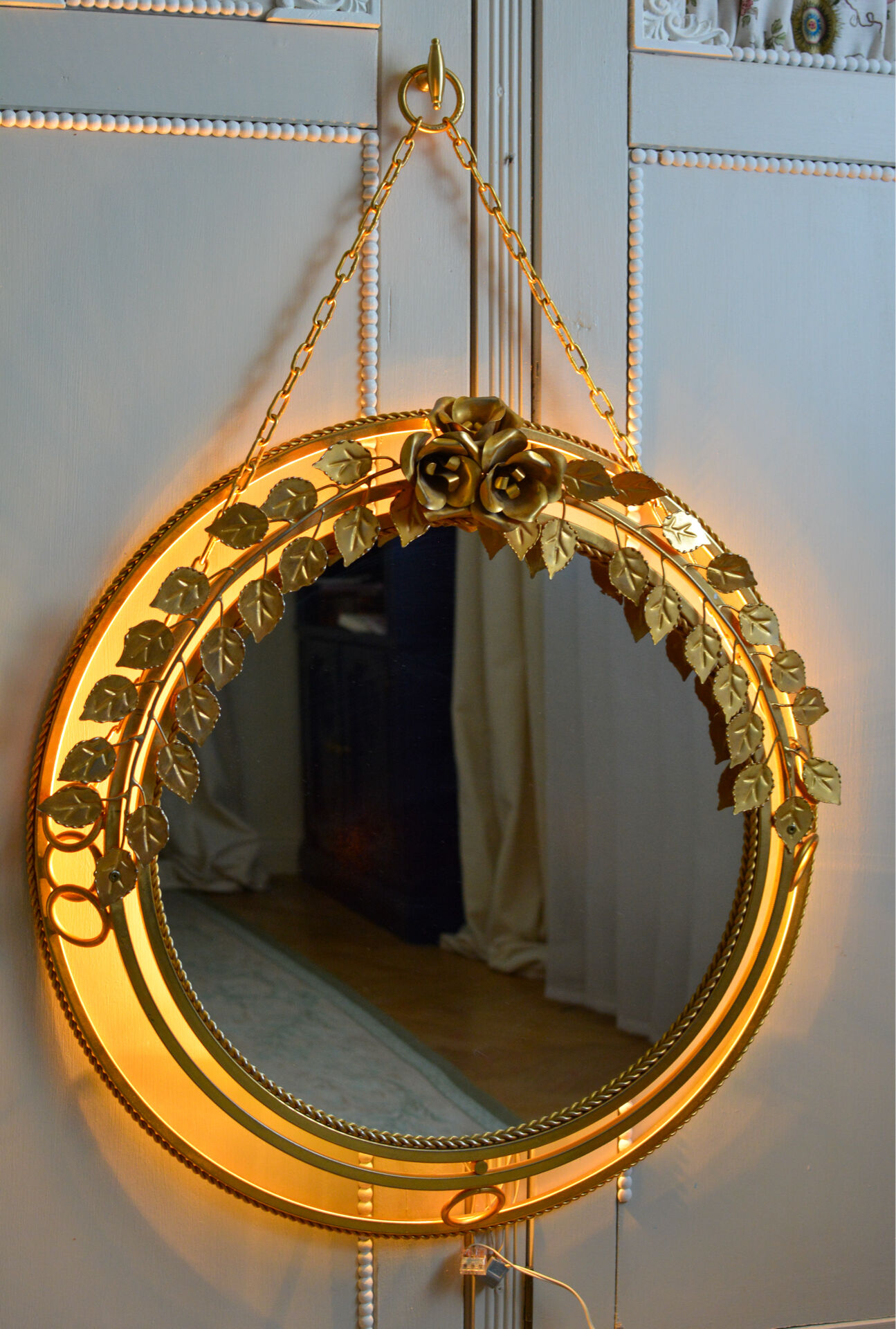 Vintage round illuminated mirror in gold metal with rose decoration.