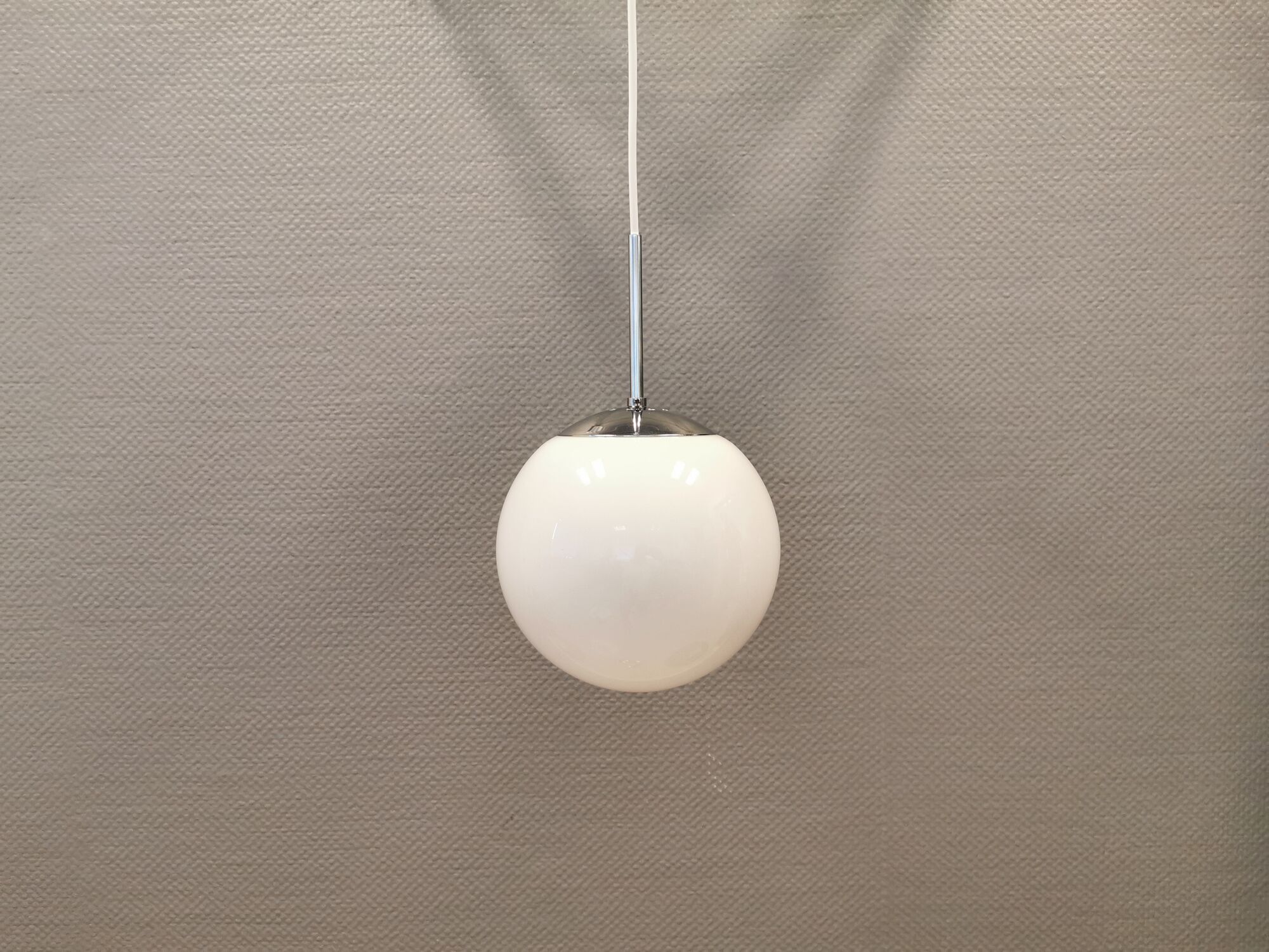 White hanging lamp with metal suspension, made with ball round opal glass shade.