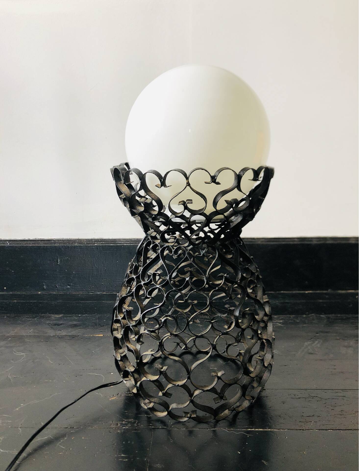 Handcrafted wrought iron lamp with a white opaline globe.