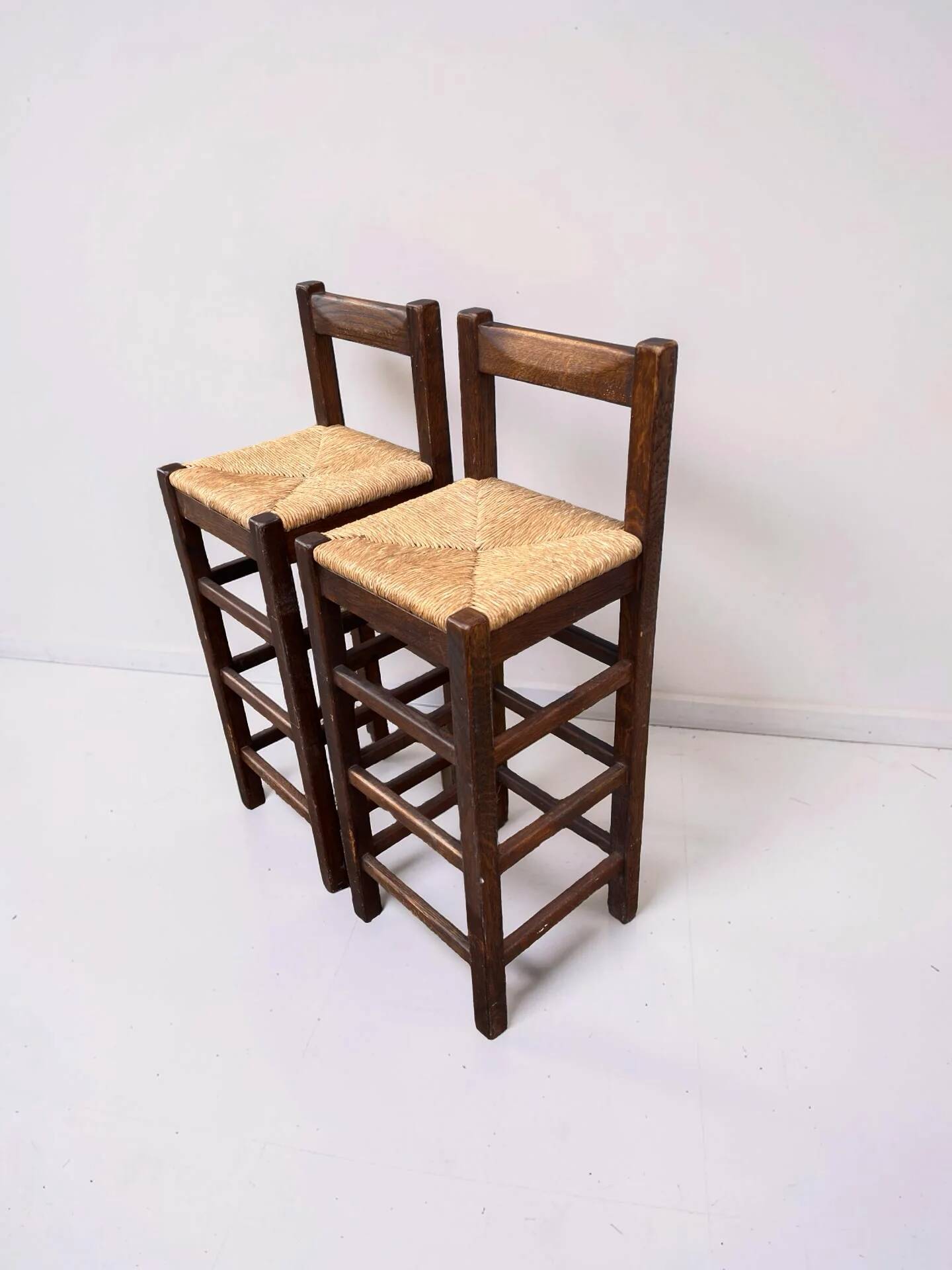 Set of 2 vintage wooden bar stools with woven straw seats.