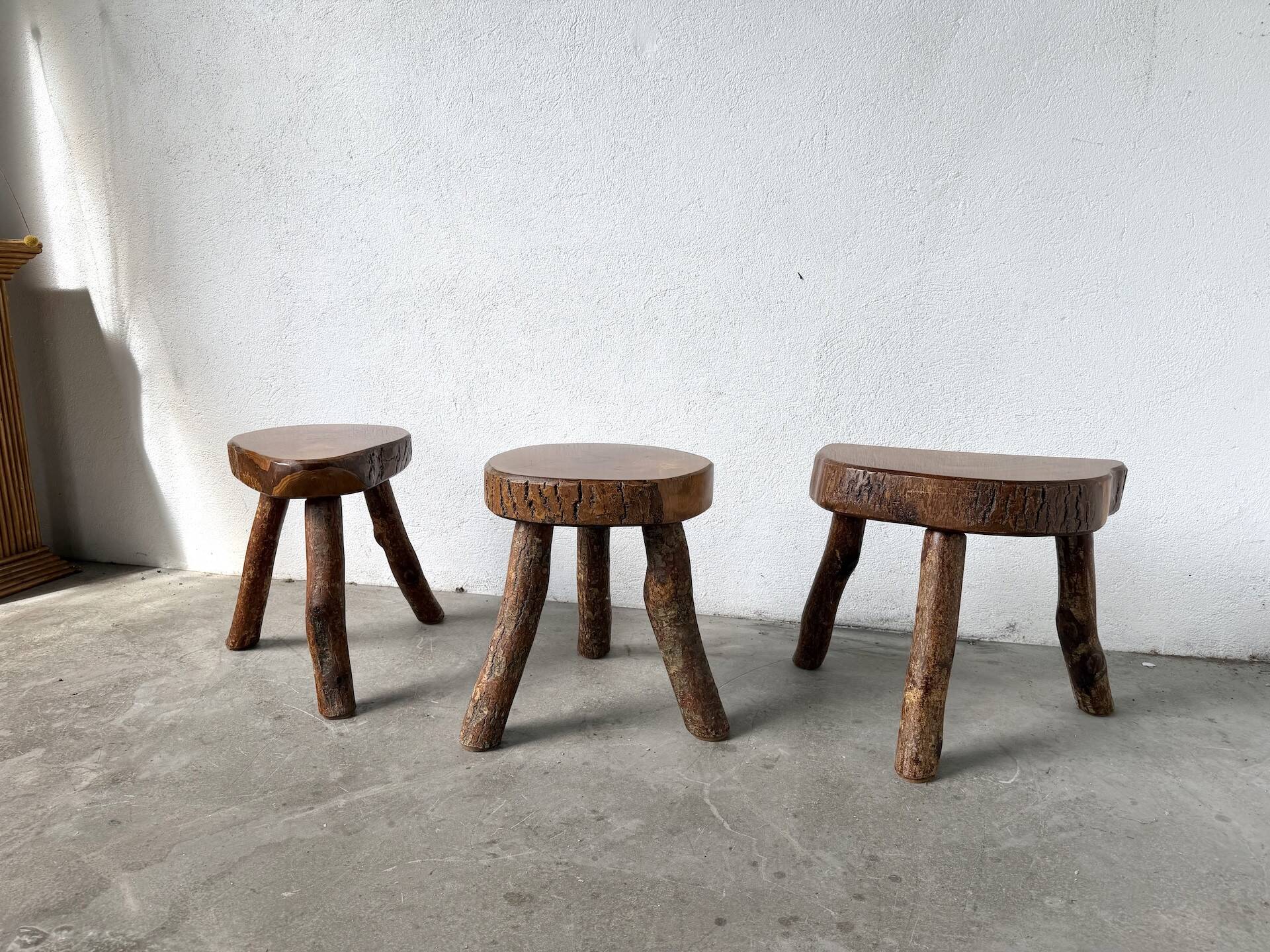 Set of three rustic solid wood tripod stools.