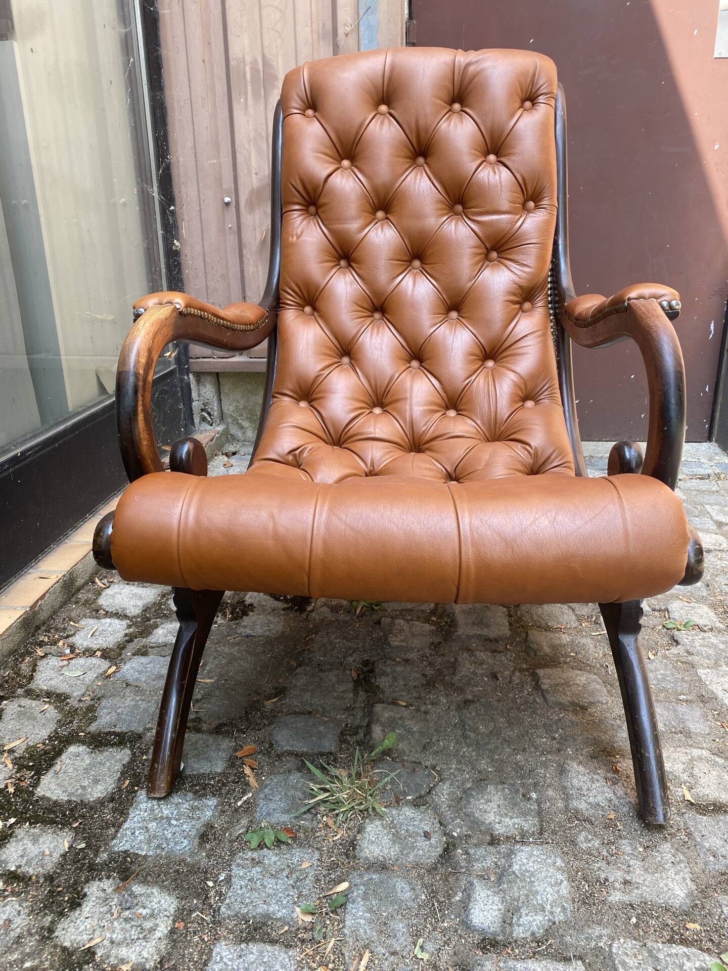 Chesterfield armchair in leather and carved solid wood