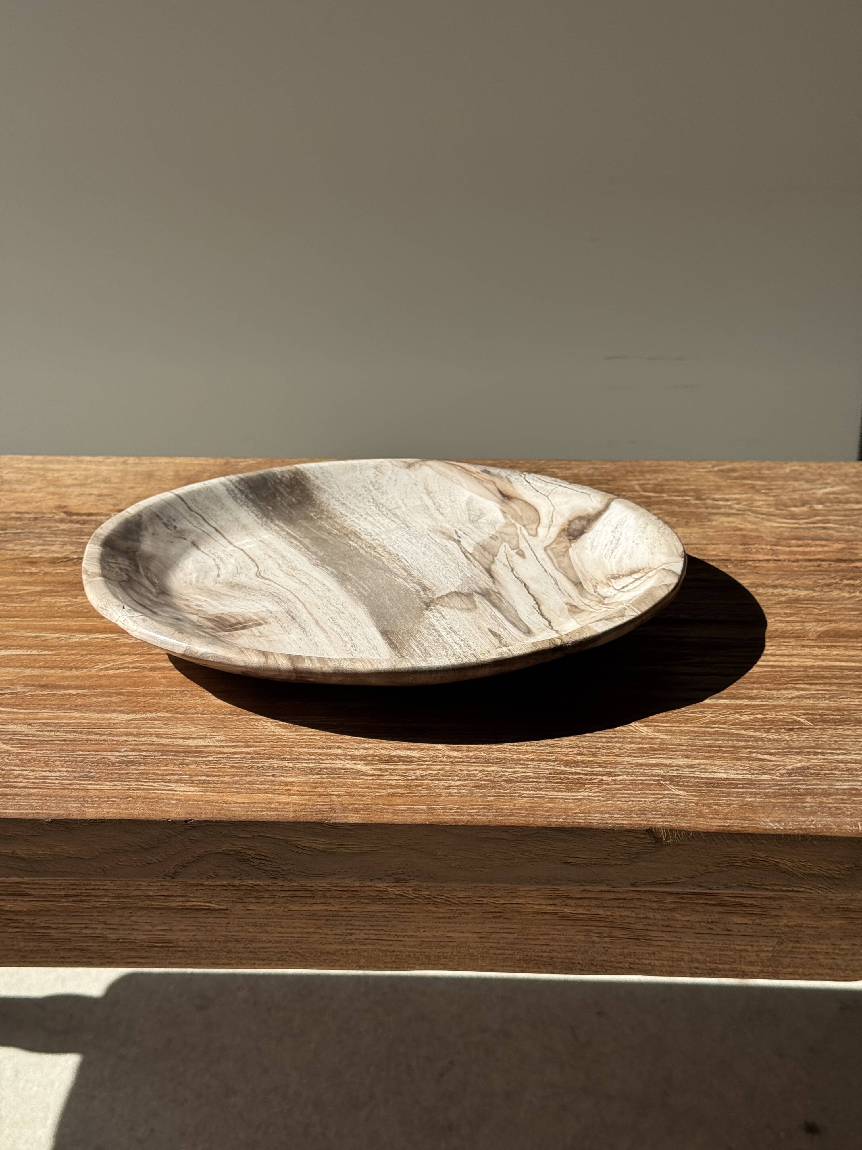 Tray, circular dish or plate made of white striped grey petrified wood.