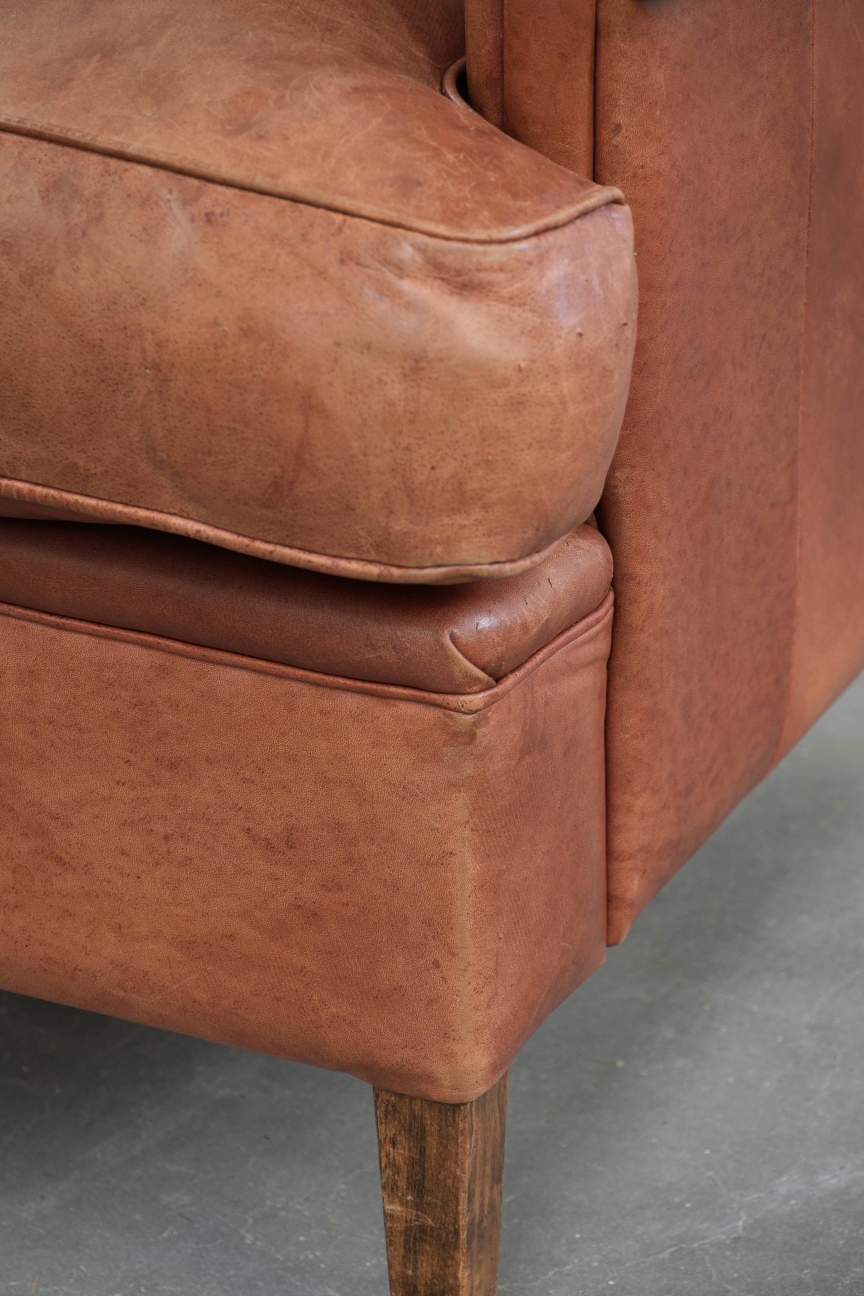 Fauteuil anglais à oreilles de couleur cognac clair en cuir de vache.