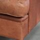 Fauteuil anglais à oreilles de couleur cognac clair en cuir de vache.