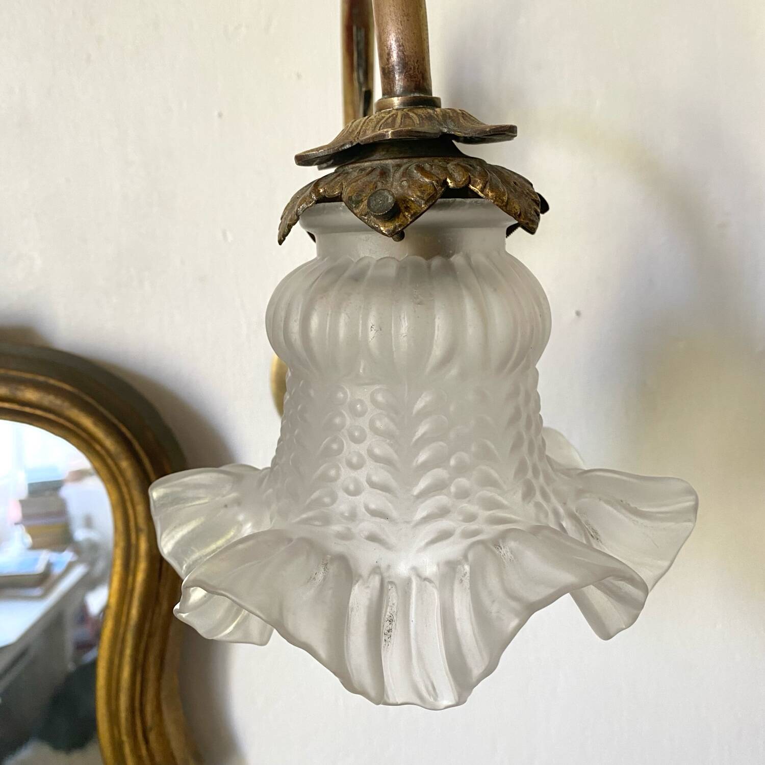 Antique brass wall light with glass shade.