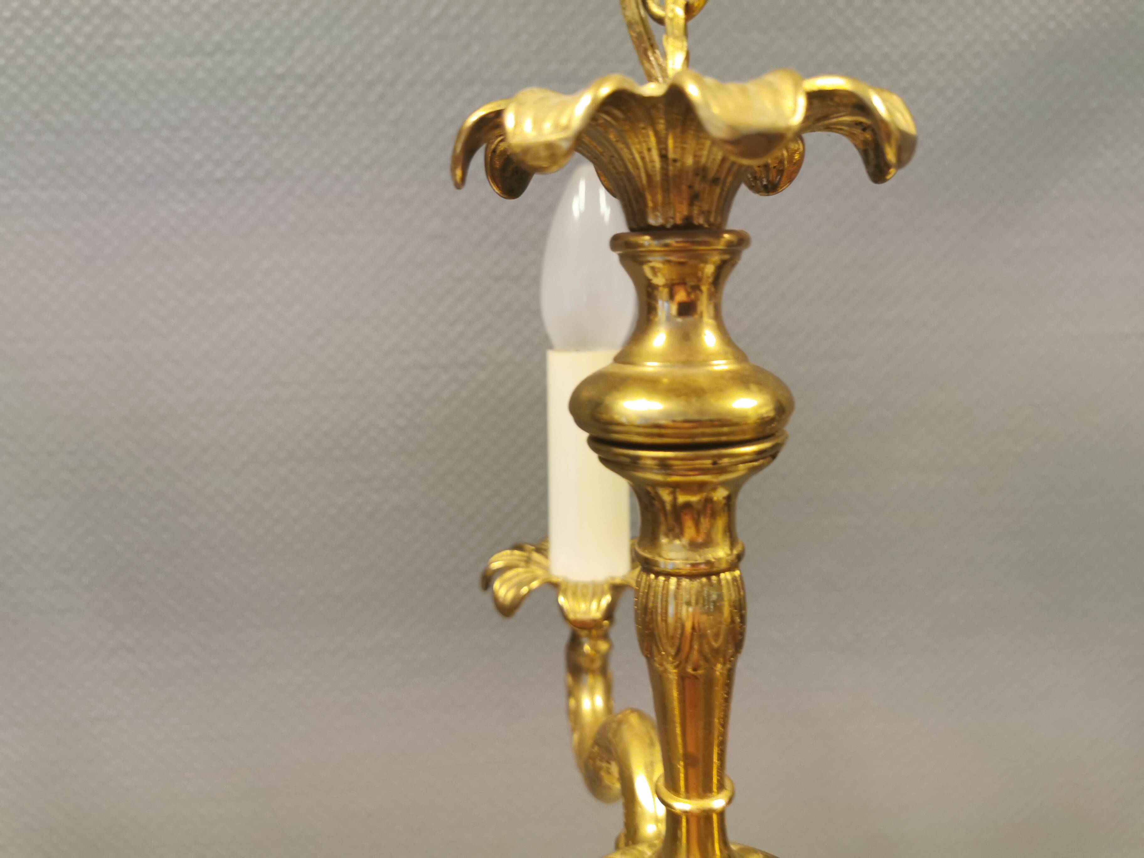 Older brass alloy chandelier with three light sources.