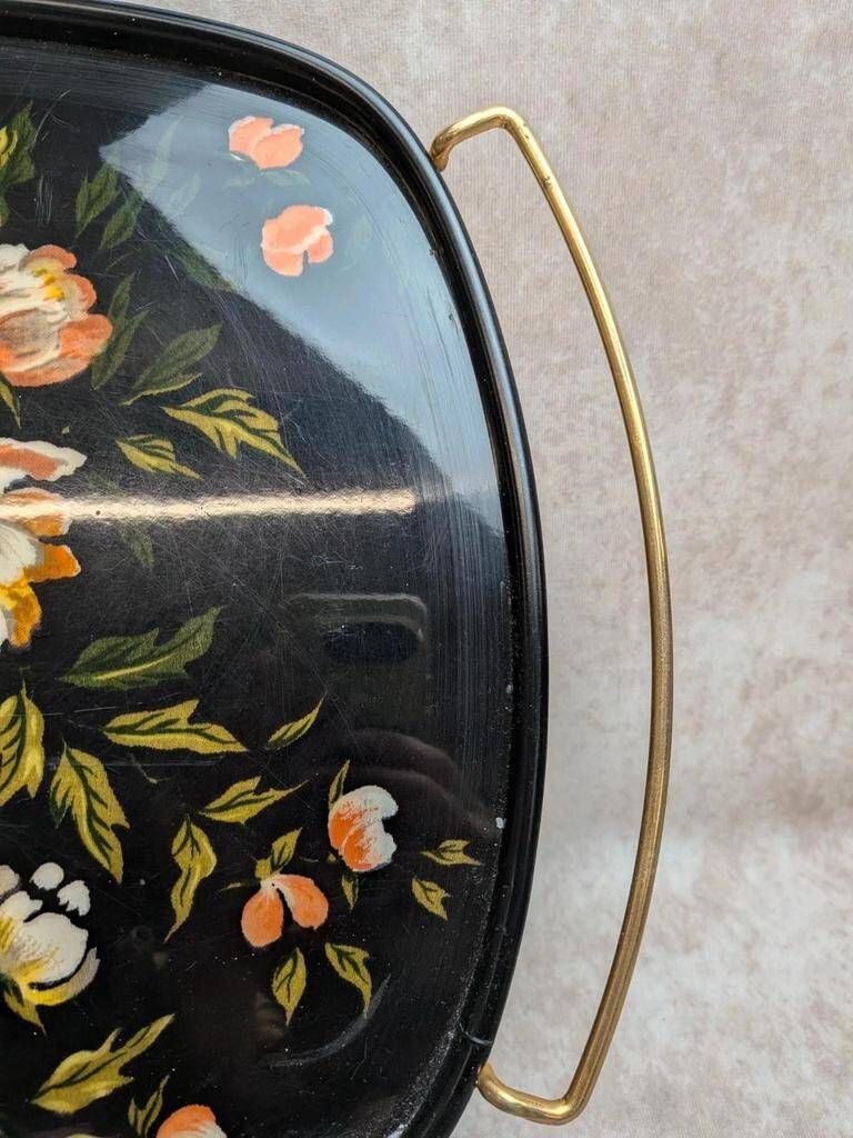 Large vintage 1960s platter with floral decoration on a black background and golden handles.