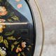 Large vintage 1960s platter with floral decoration on a black background and golden handles.