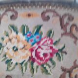 Antique carved stool in an arched shape covered in handmade tapestry