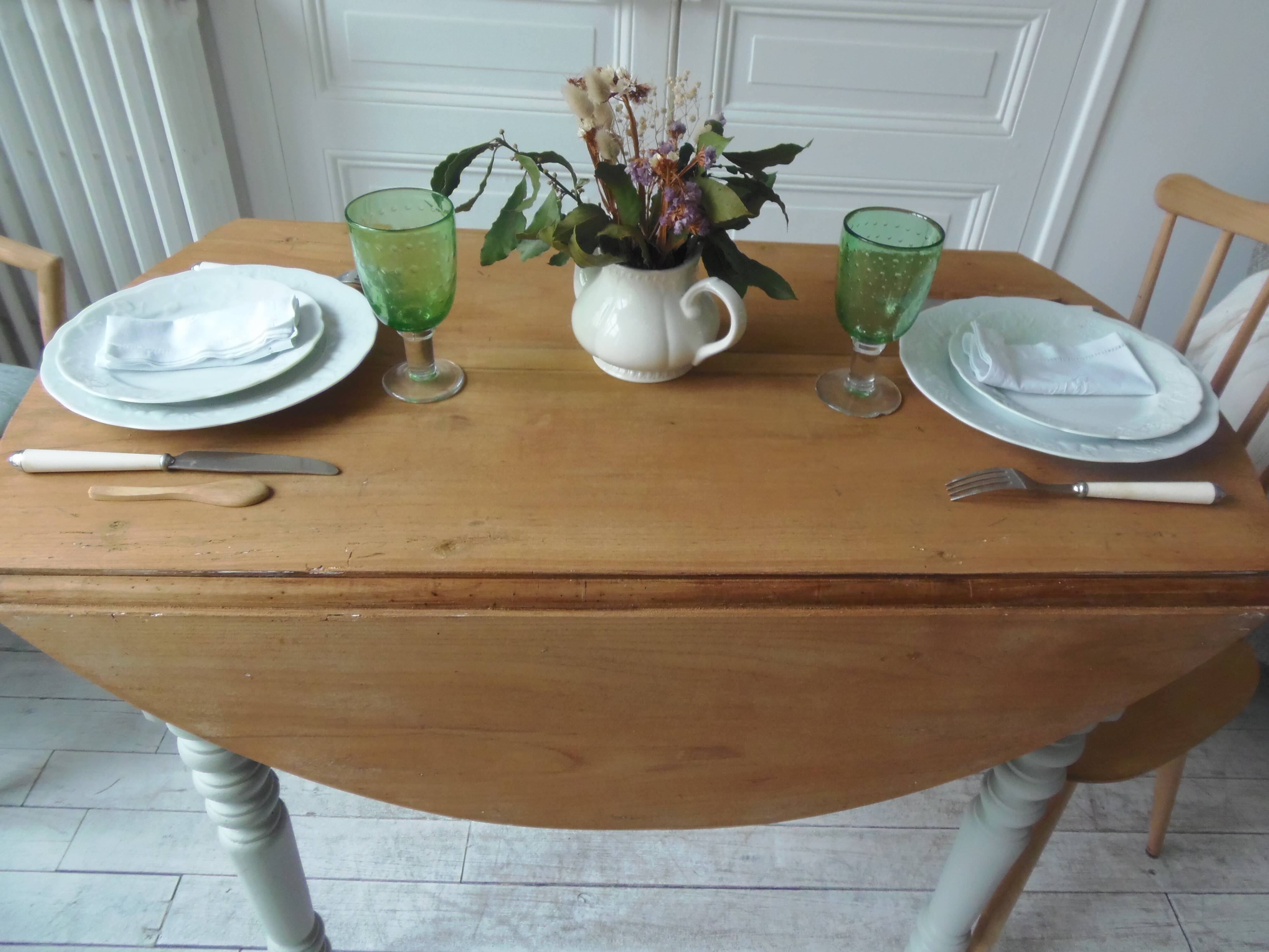 Raised walnut table with drop-leaf top, base on verdigris castors.