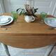 Raised walnut table with drop-leaf top, base on verdigris castors.