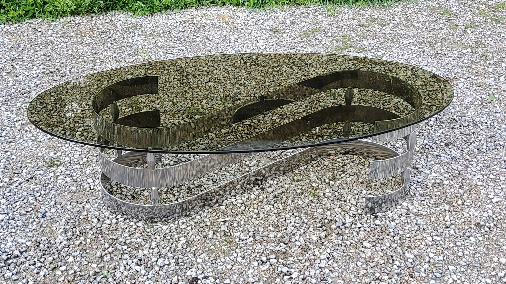 Oval coffee table of the 70s chromed metal base in s smoked glass top