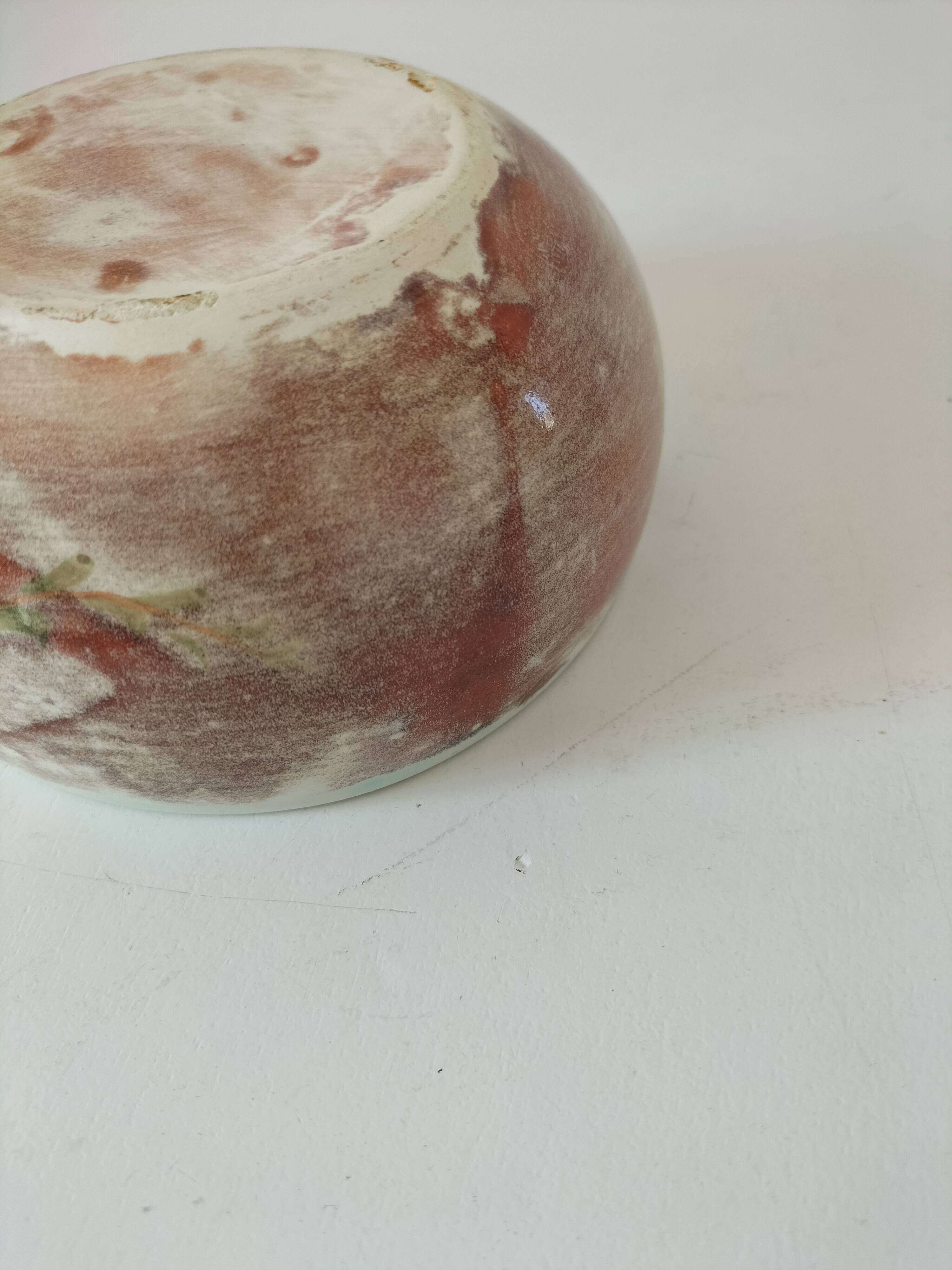 Red-orange glazed ceramic workshop bowl with floral decoration.