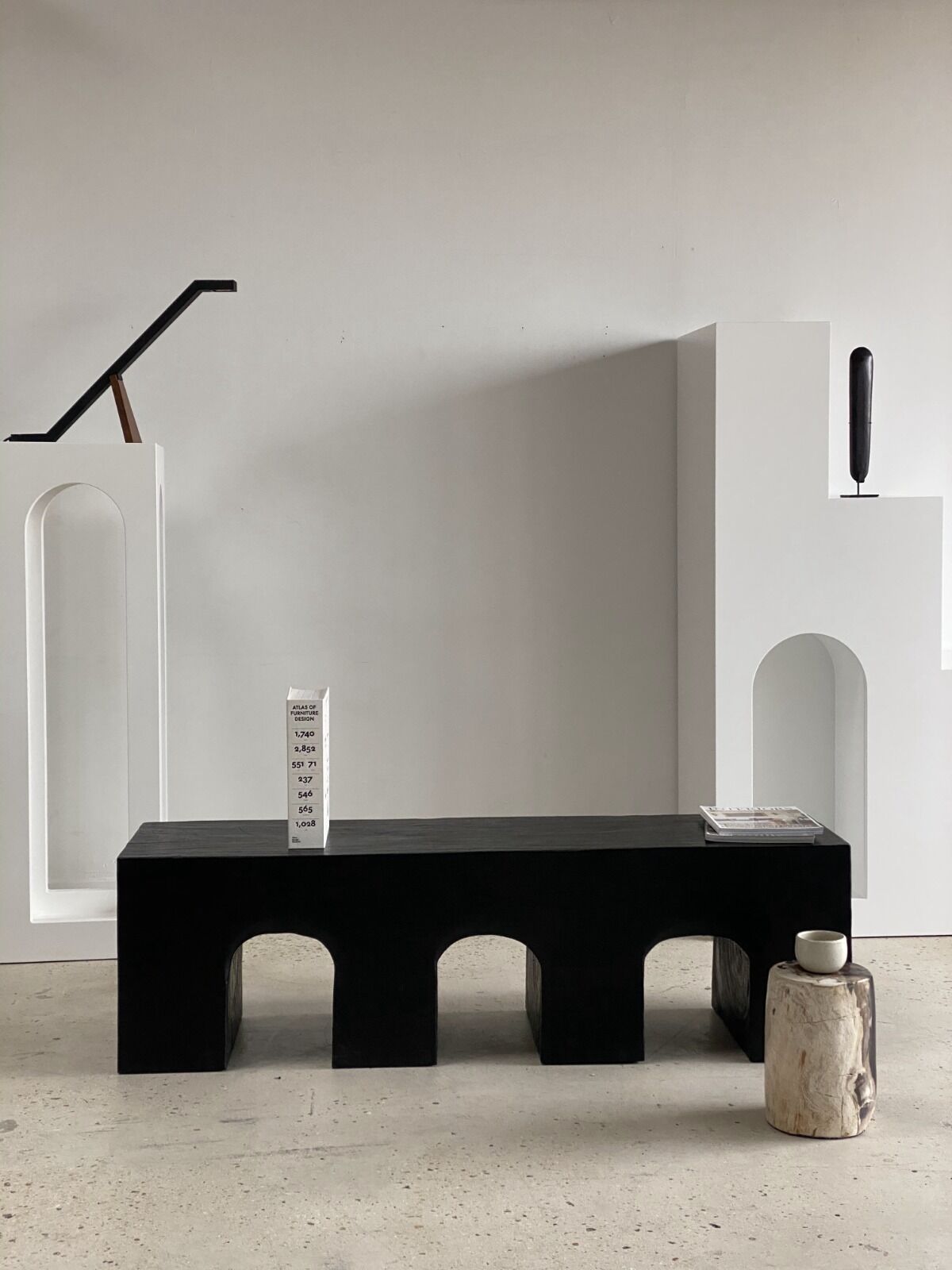 Black solid monoxyl wood bench carved into 3 arches