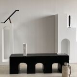 Black solid monoxyl wood bench carved into 3 arches