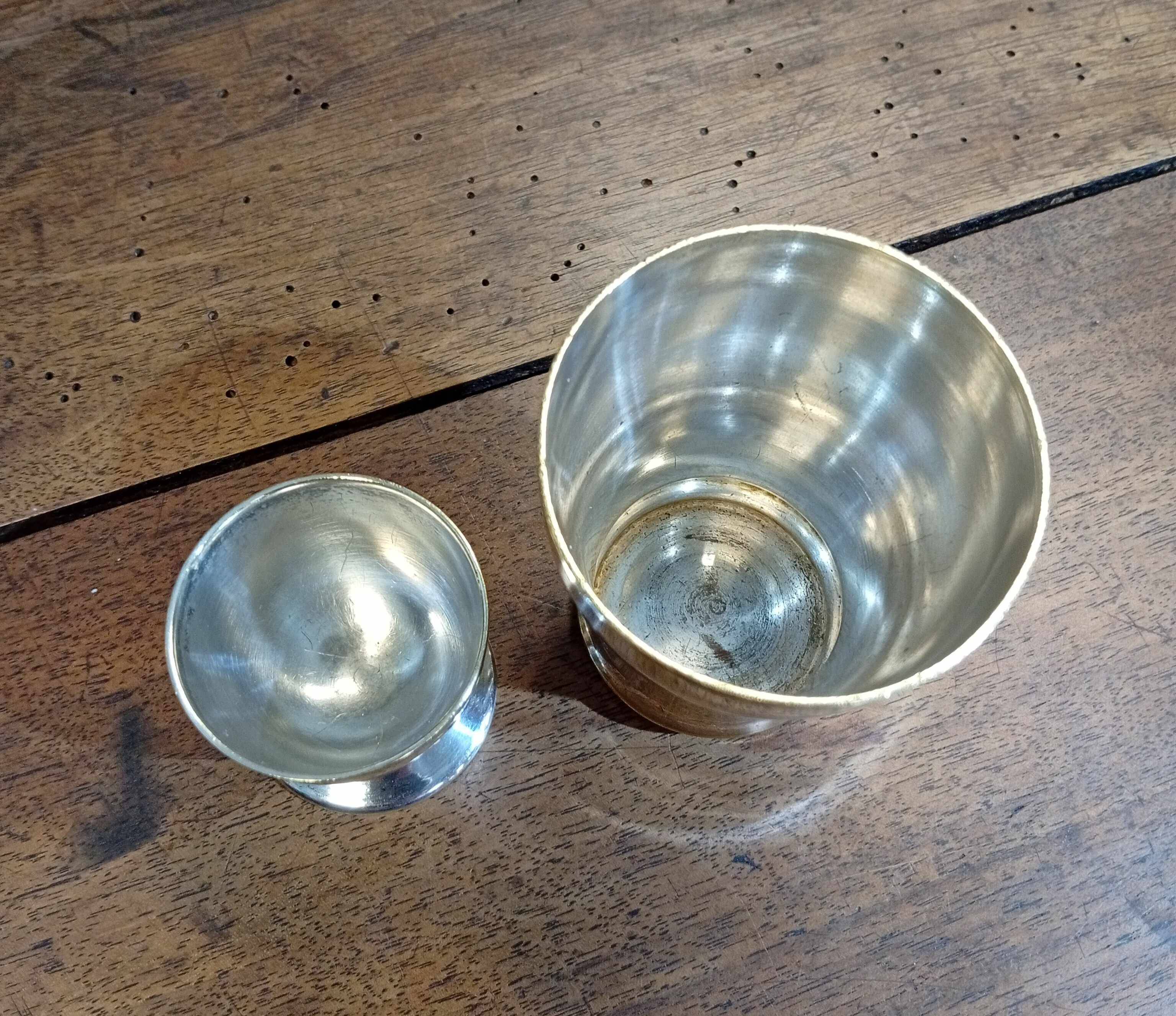 Silver-plated cup and egg cup set with floral decoration.