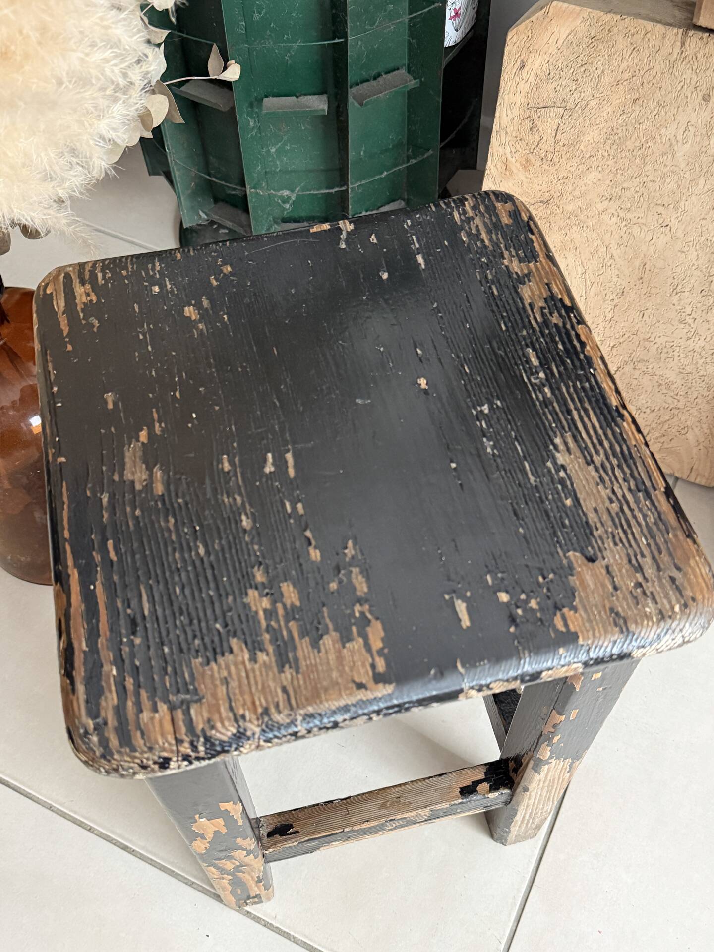 Solid wood stool with a worn black patina.