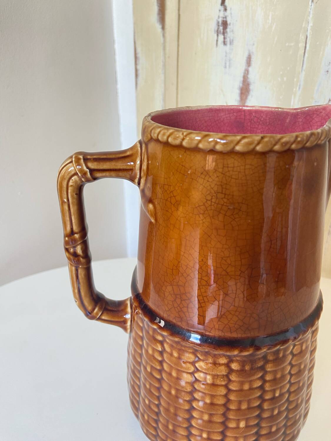 Antique vintage ceramic pitcher or jug from Sarreguemines, France. Brown with a pink interior, imitation basket.