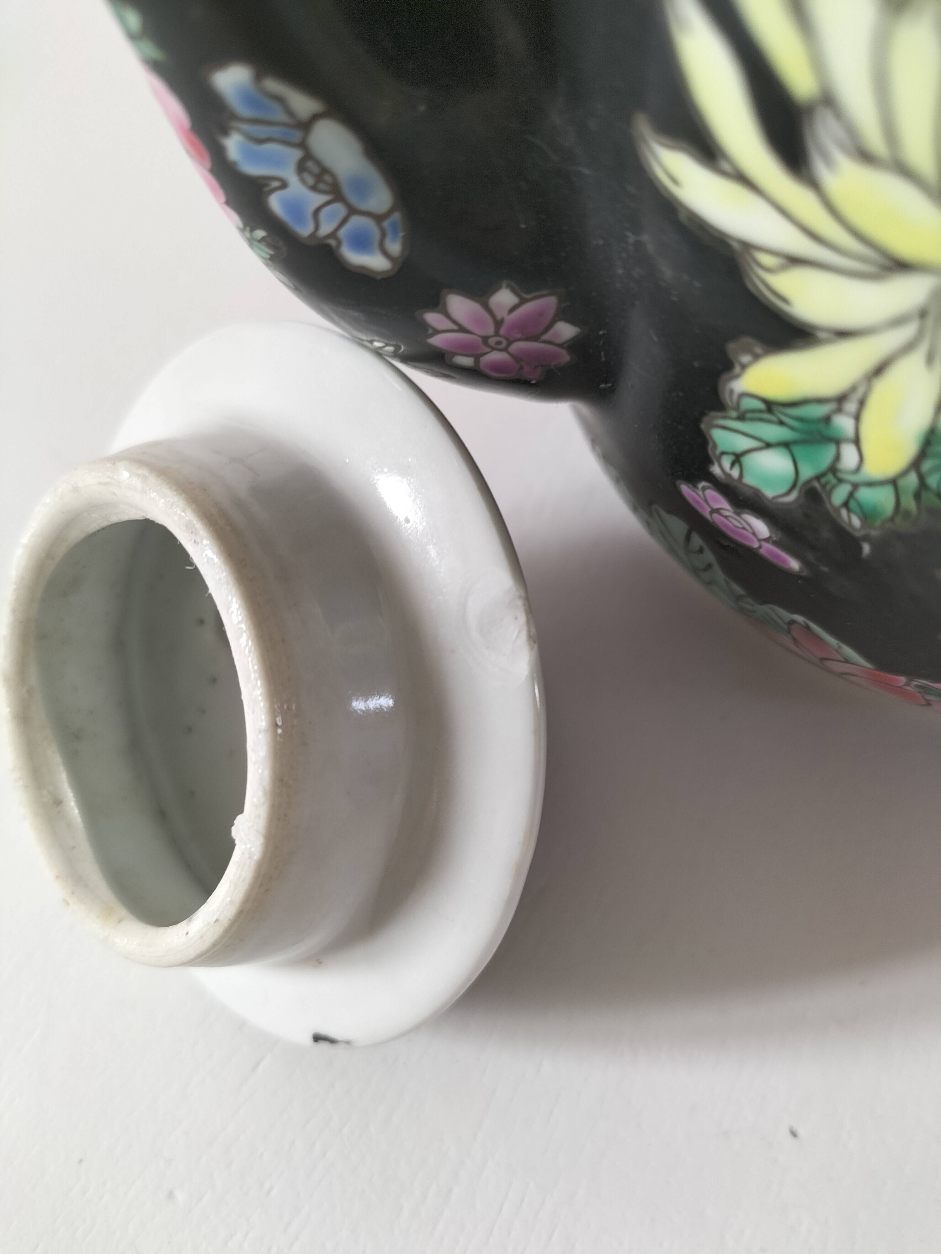 Vintage Chinese teapot with floral polychrome decoration on a black background.