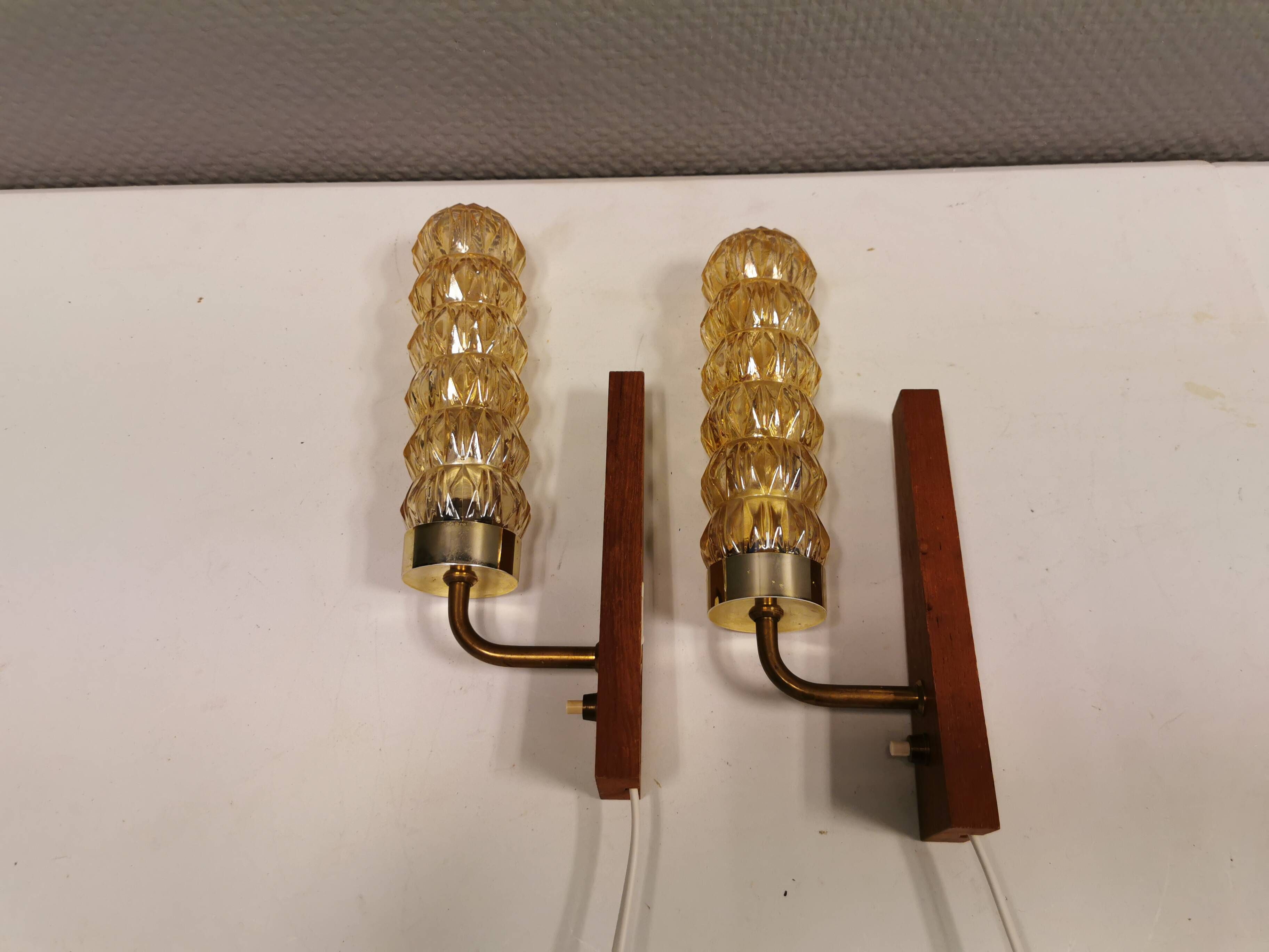 A set of Danish wall lights in champagne coloured glass with brass and teak.