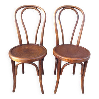 pair of round wooden chairs with a pattern on the seat