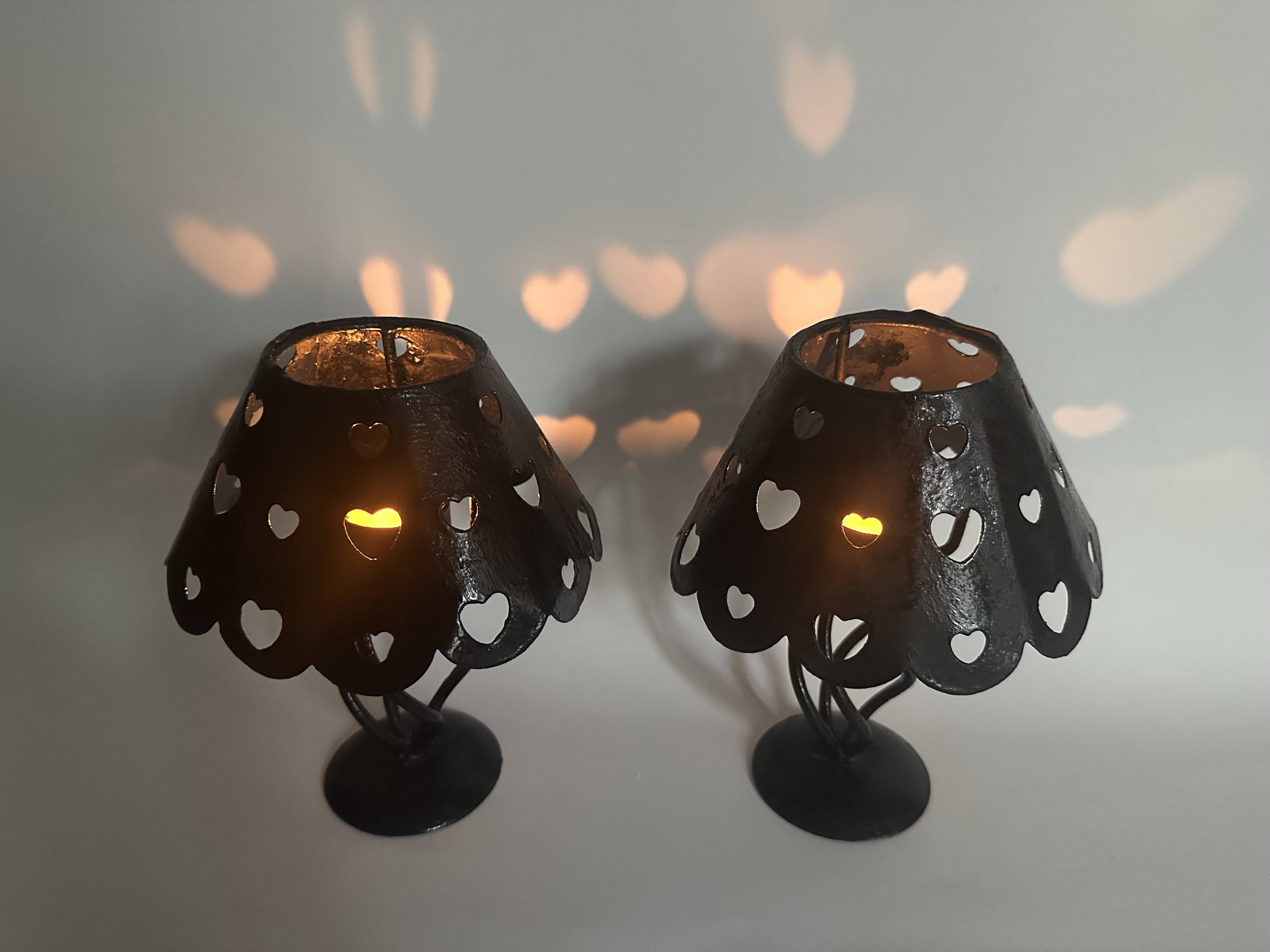 Pair of black wrought iron lanterns with heart patterns, romantic style.