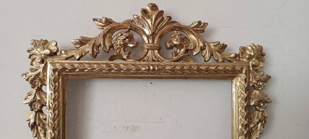 Mirror with a carved wooden frame in an antique style in pure gold.