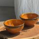 Pair of small orange bowls with black edging