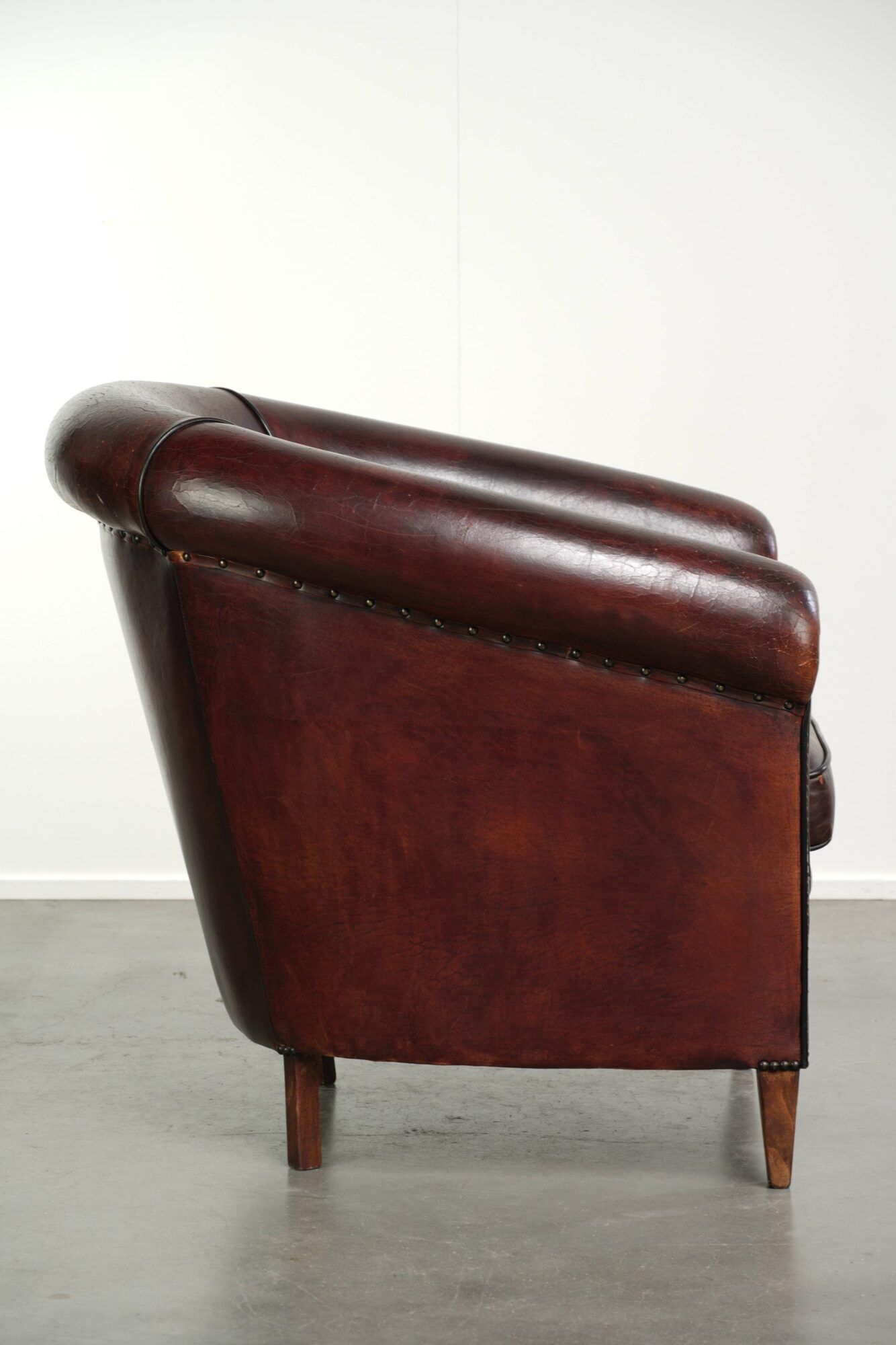 Vintage sheepskin club armchair with decorative nails and black piping