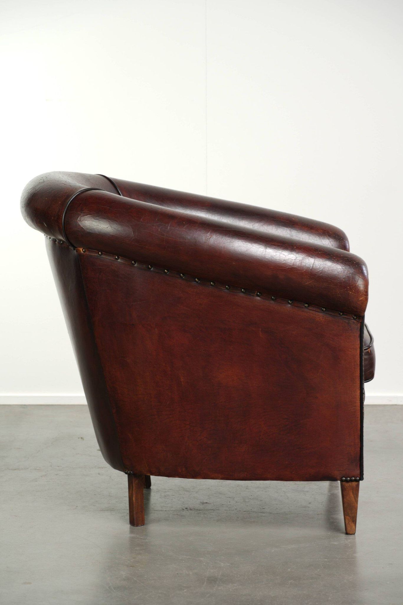 Vintage sheepskin club armchair with decorative nails and black piping