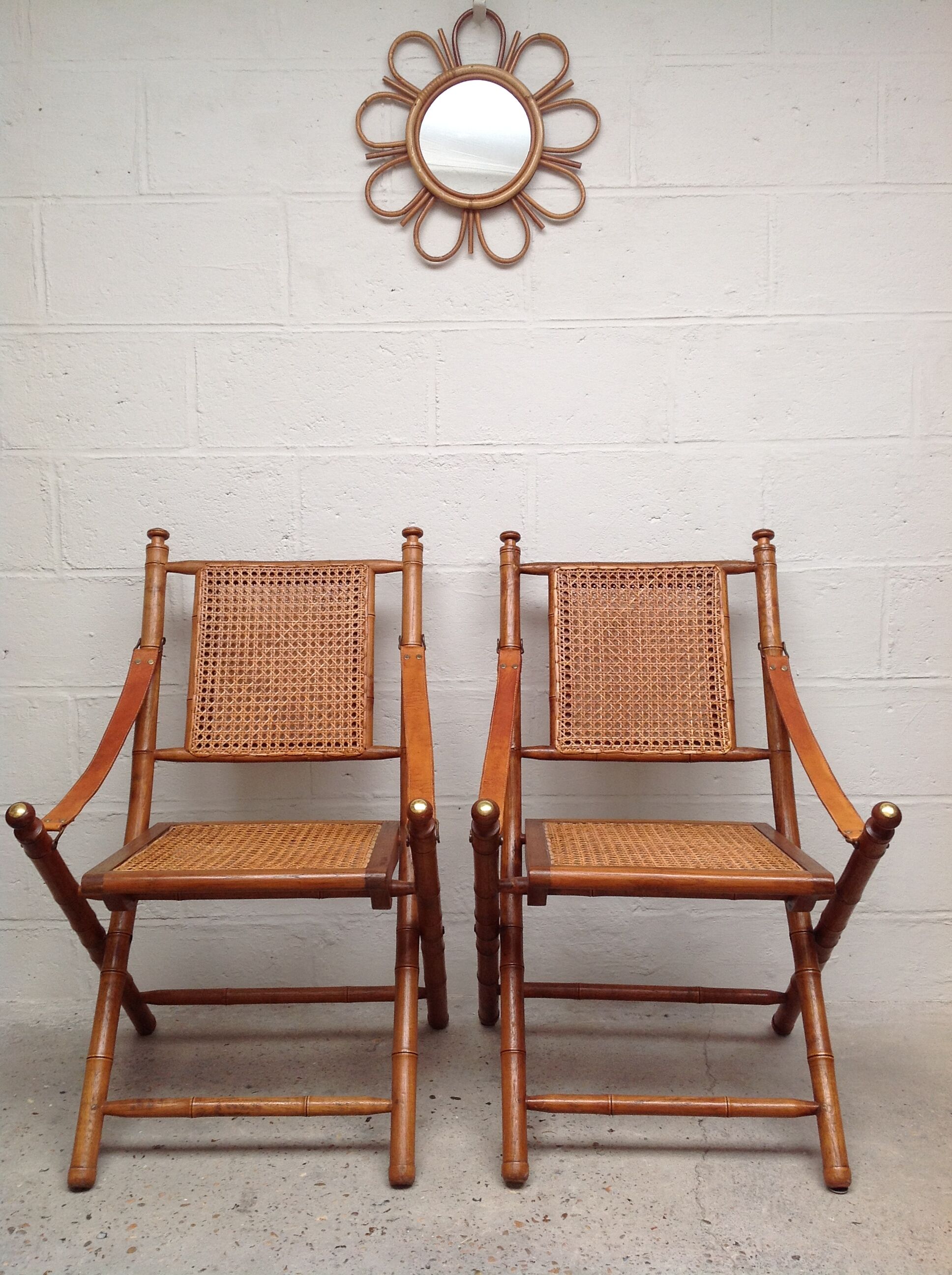 Pair of folding chairs in bamboo and caning, leather and brass