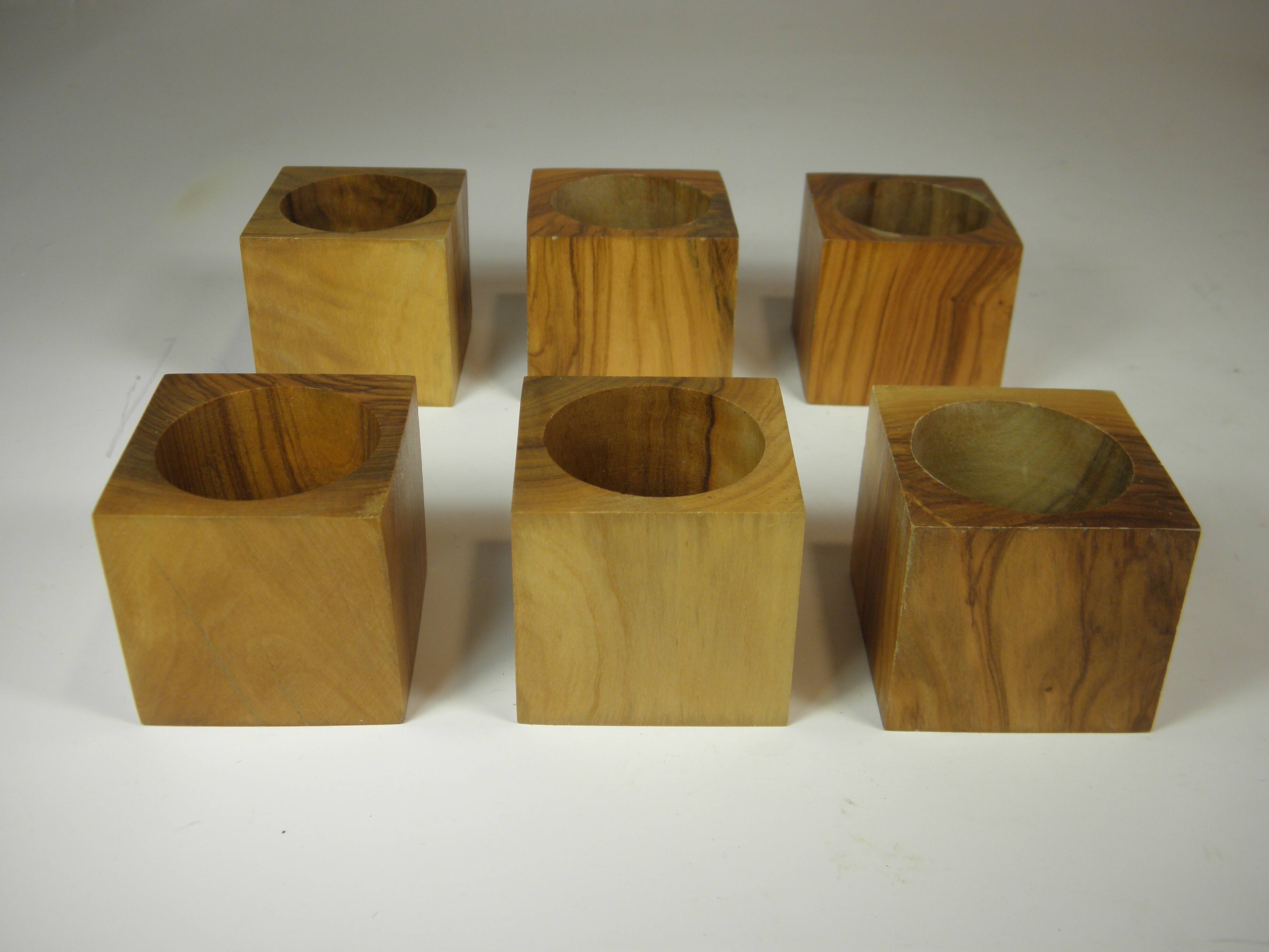Six egg cups on a wooden tray.