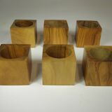 Six egg cups on a wooden tray.