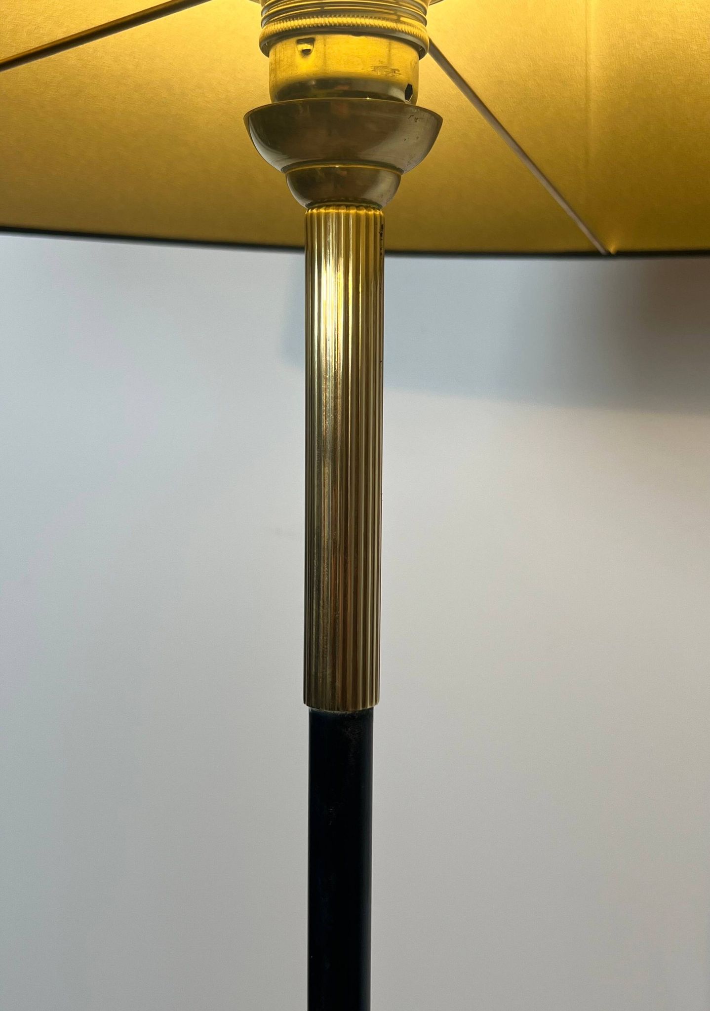 Designer floor lamp in black lacquered metal and brass, incorporating a magazine rack
