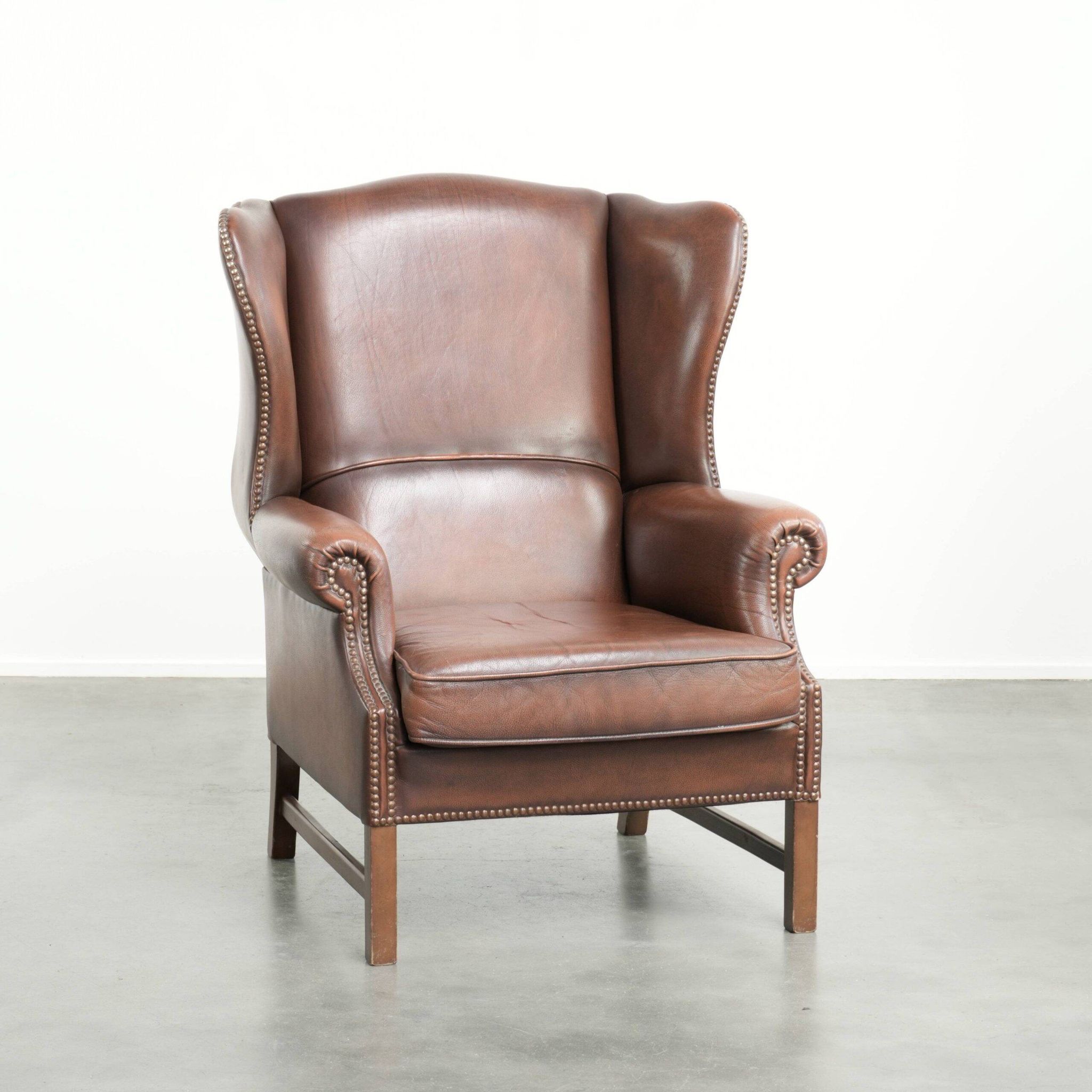 Fauteuil à oreilles en cuir de vache confortable de style anglais avec un look intemporel.