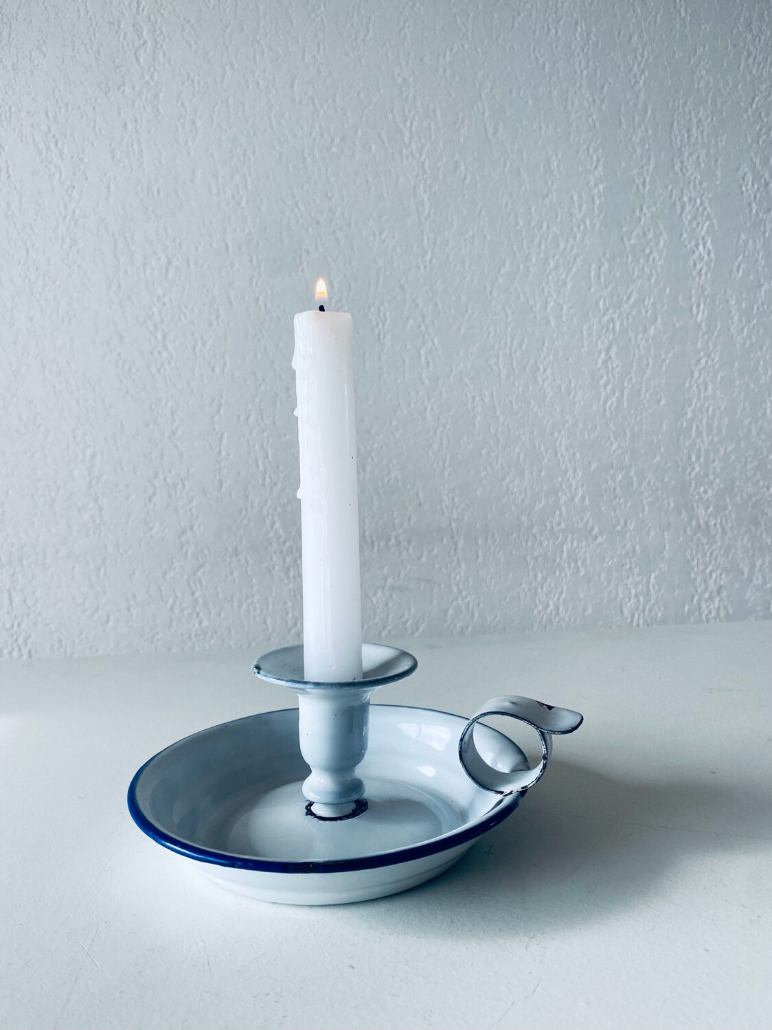 Old candle holder in white enameled metal