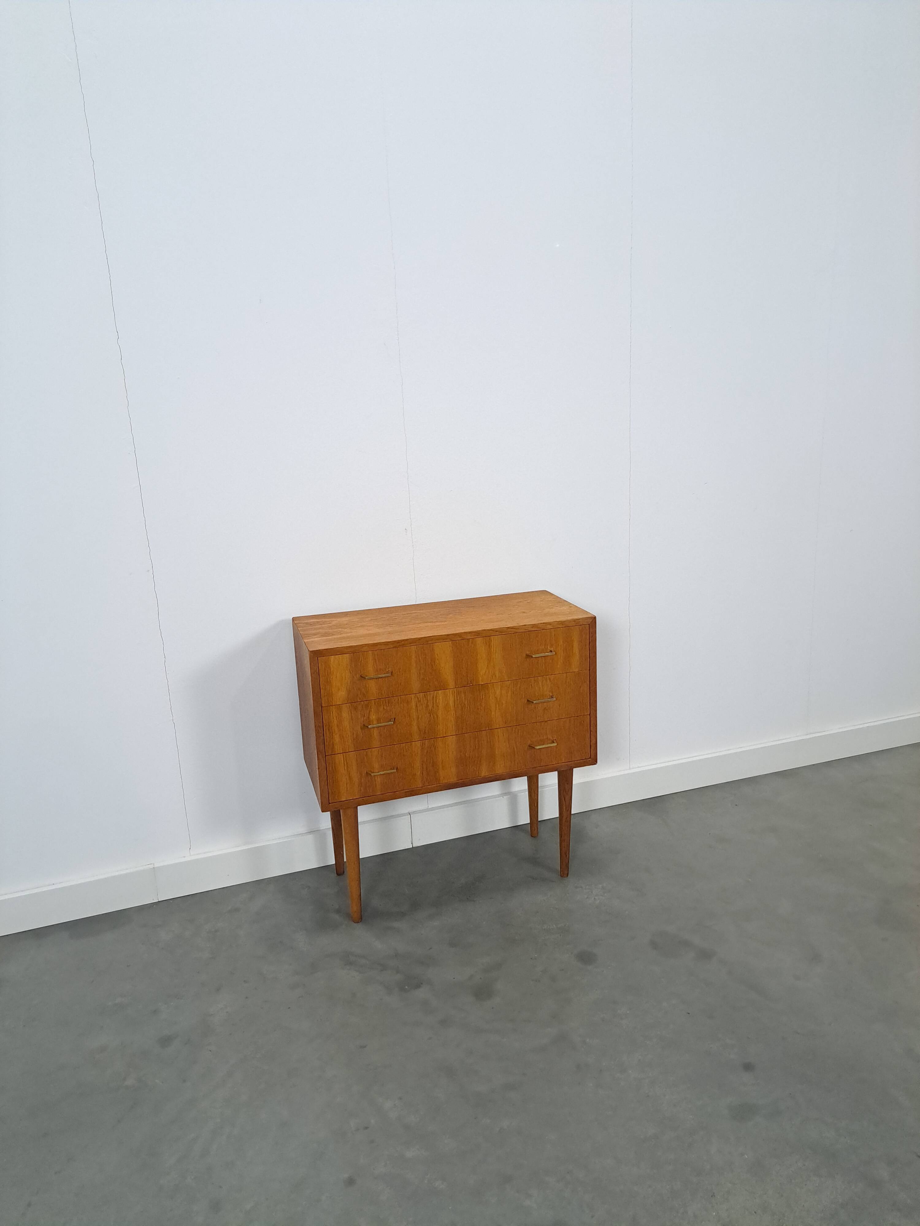 Commode danoise avec de hauts pieds et des poignées dorées.
