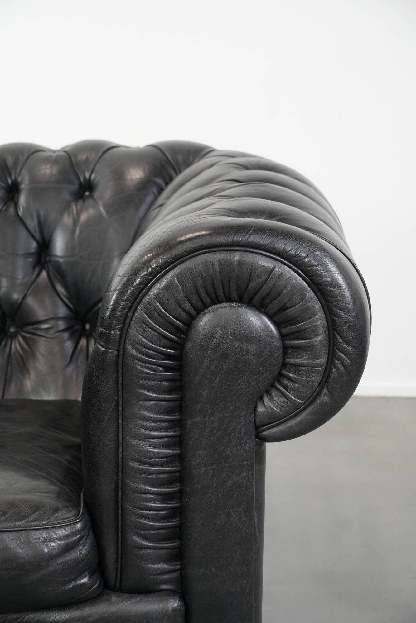 Set of a black cowhide leather Chesterfield armchair and matching ottoman